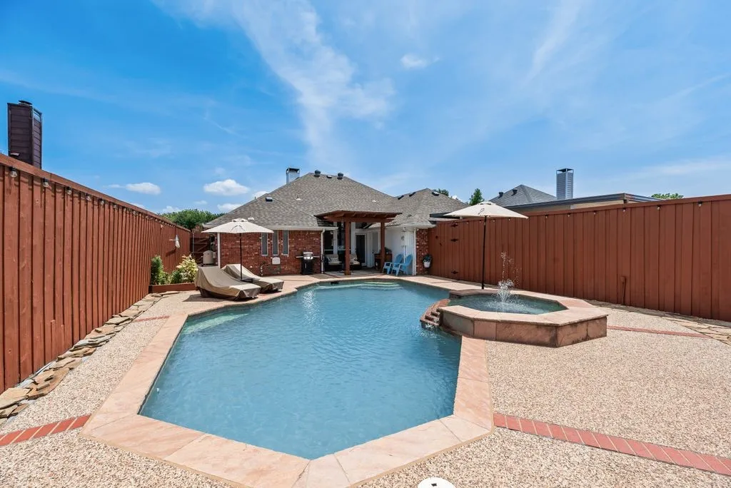 In-ground swimming pool with integrated spa and fountain feature