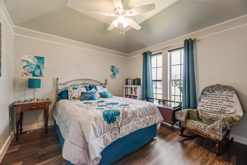 Vaulted ceiling with a ceiling fan, wood-finish flooring, and two large windows