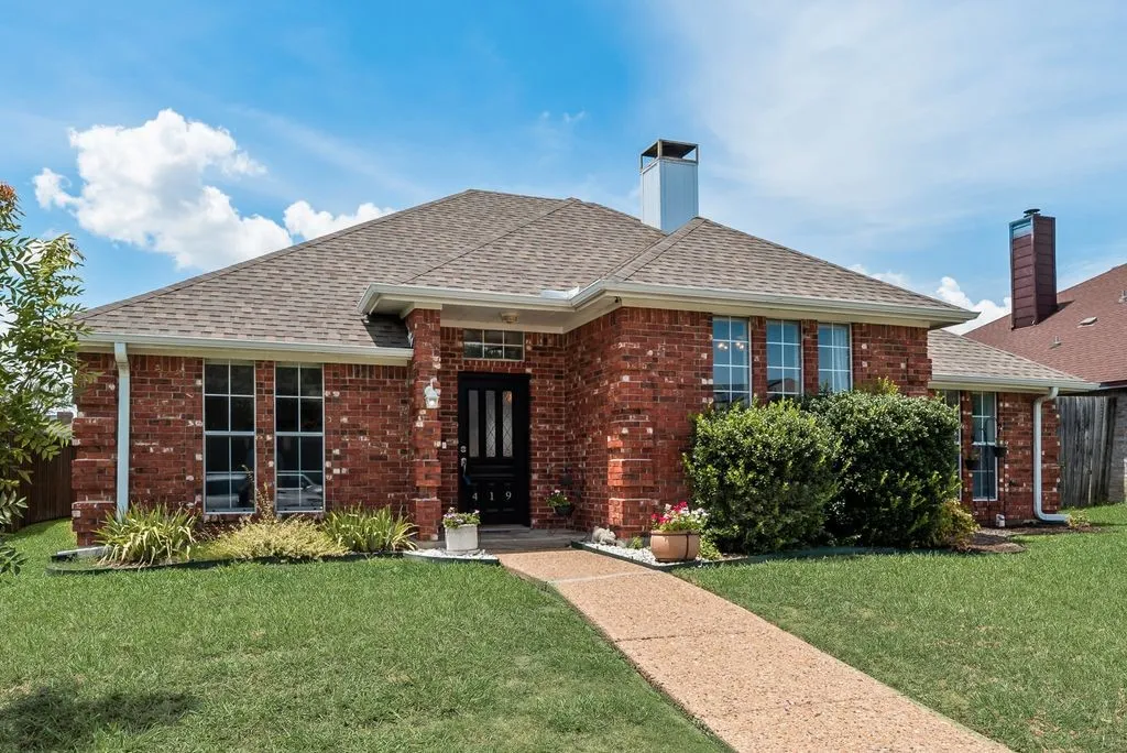 Red brick exterior featuring a brown shingle roof and white gutters
