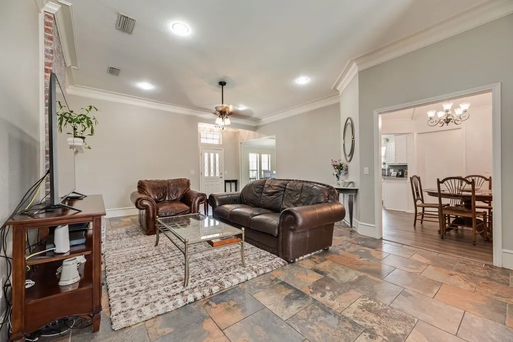 Living area featuring slate tile flooring, recessed lighting, and crown molding