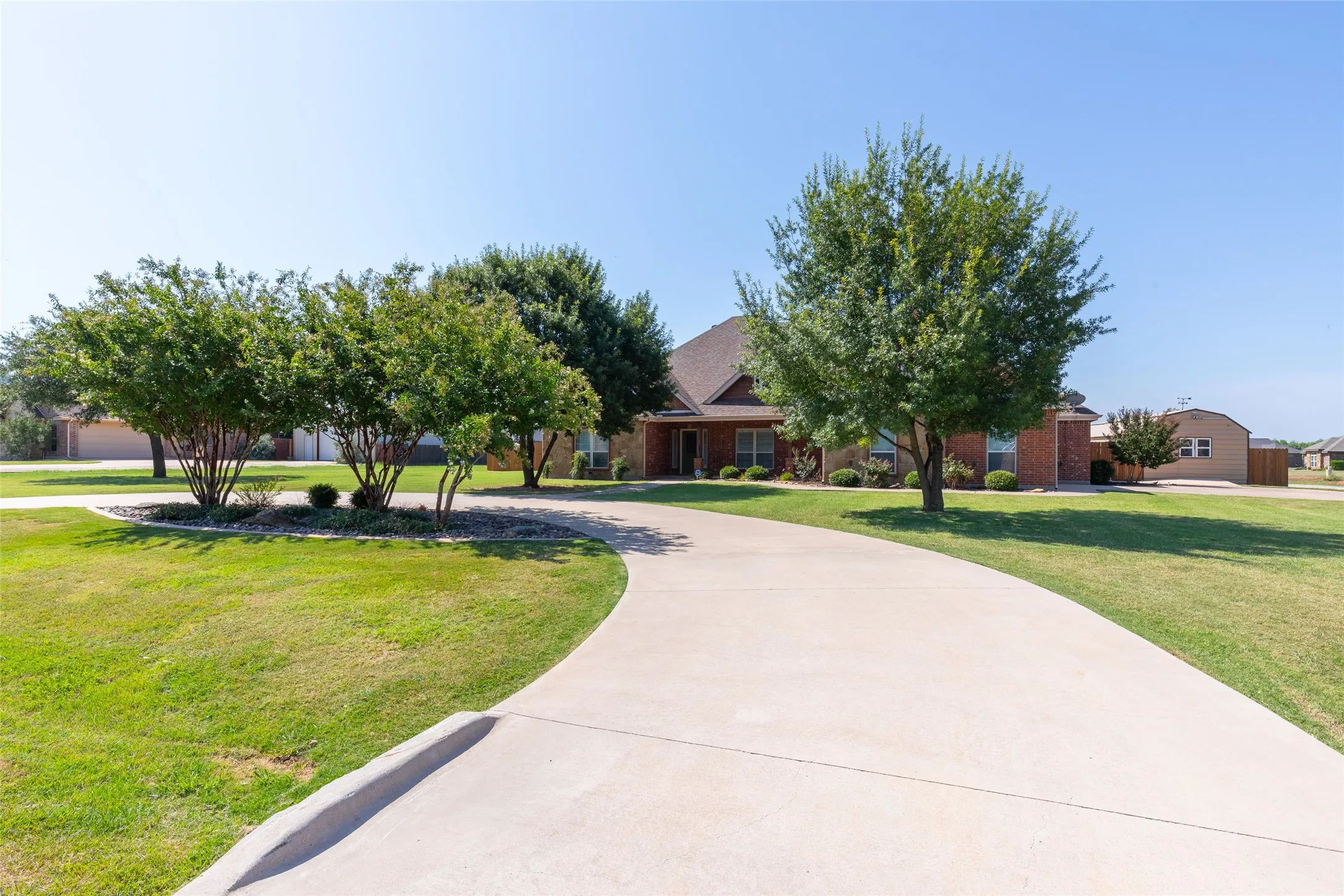 Front of home, fully landscaped, with a large circular driveway