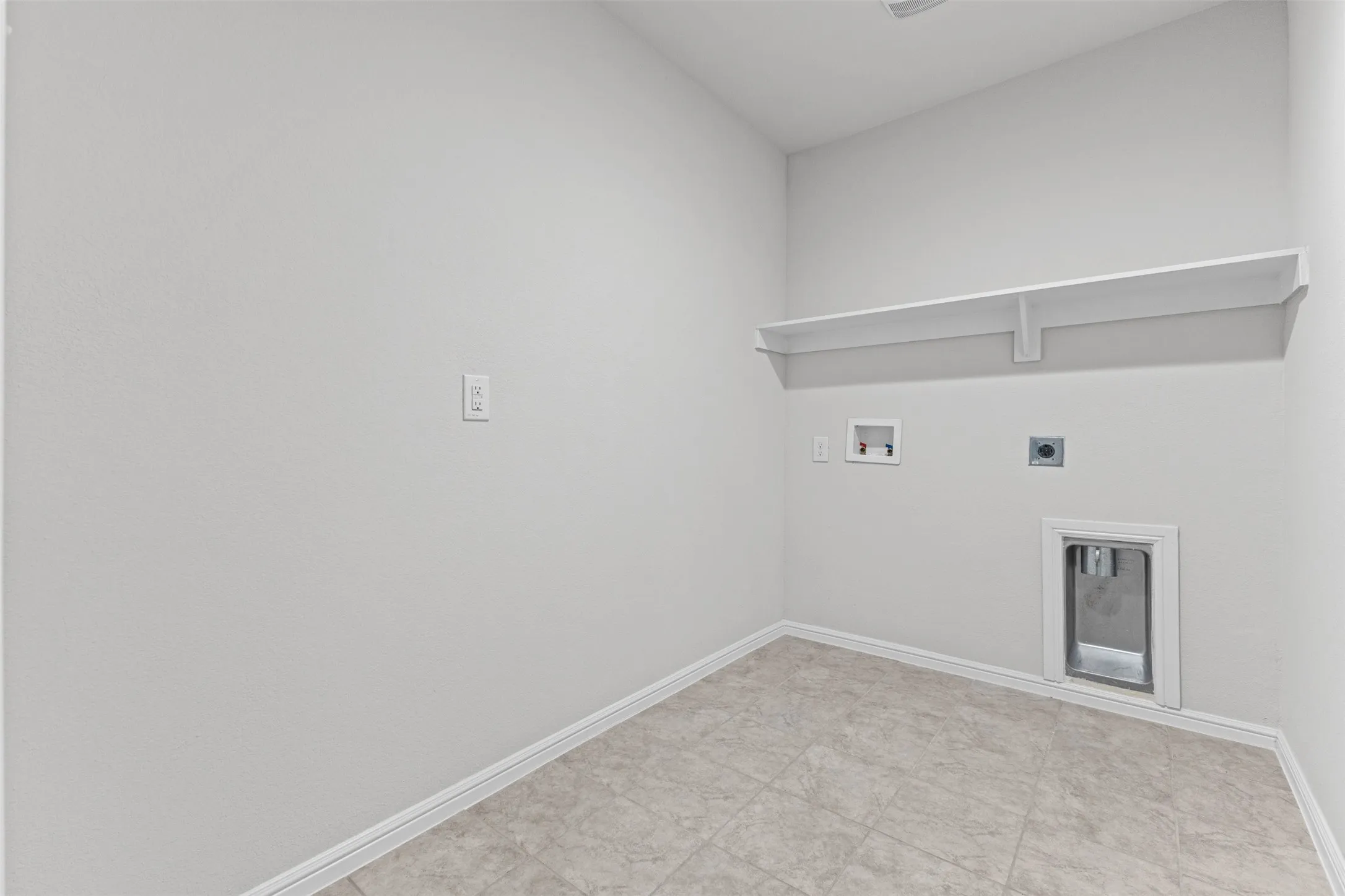 Utility room with light-toned tiled flooring and a white wall shelf