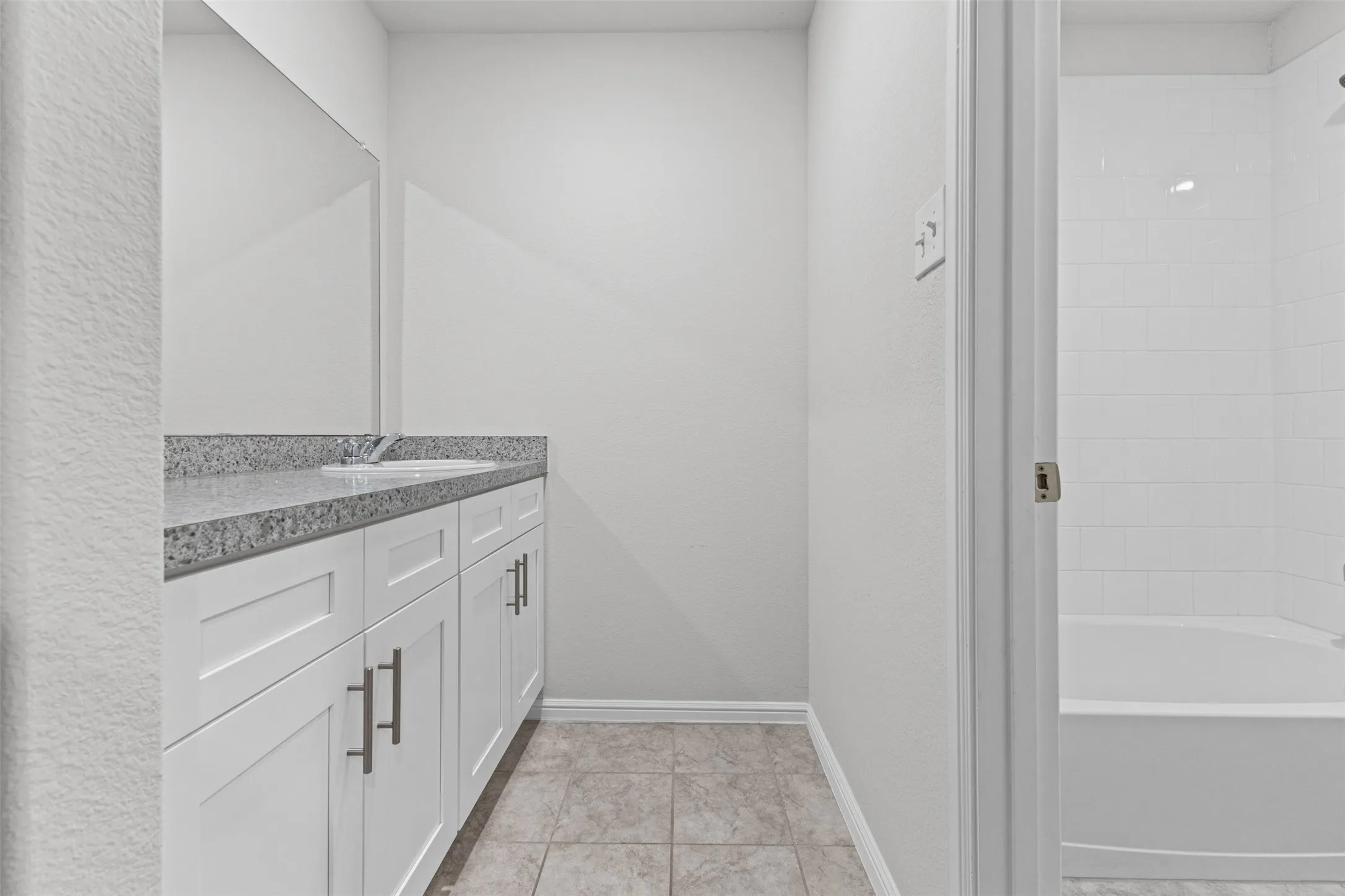 Bathroom featuring a white vanity with silver hardware, an integrated sink, and a speckled countertop
