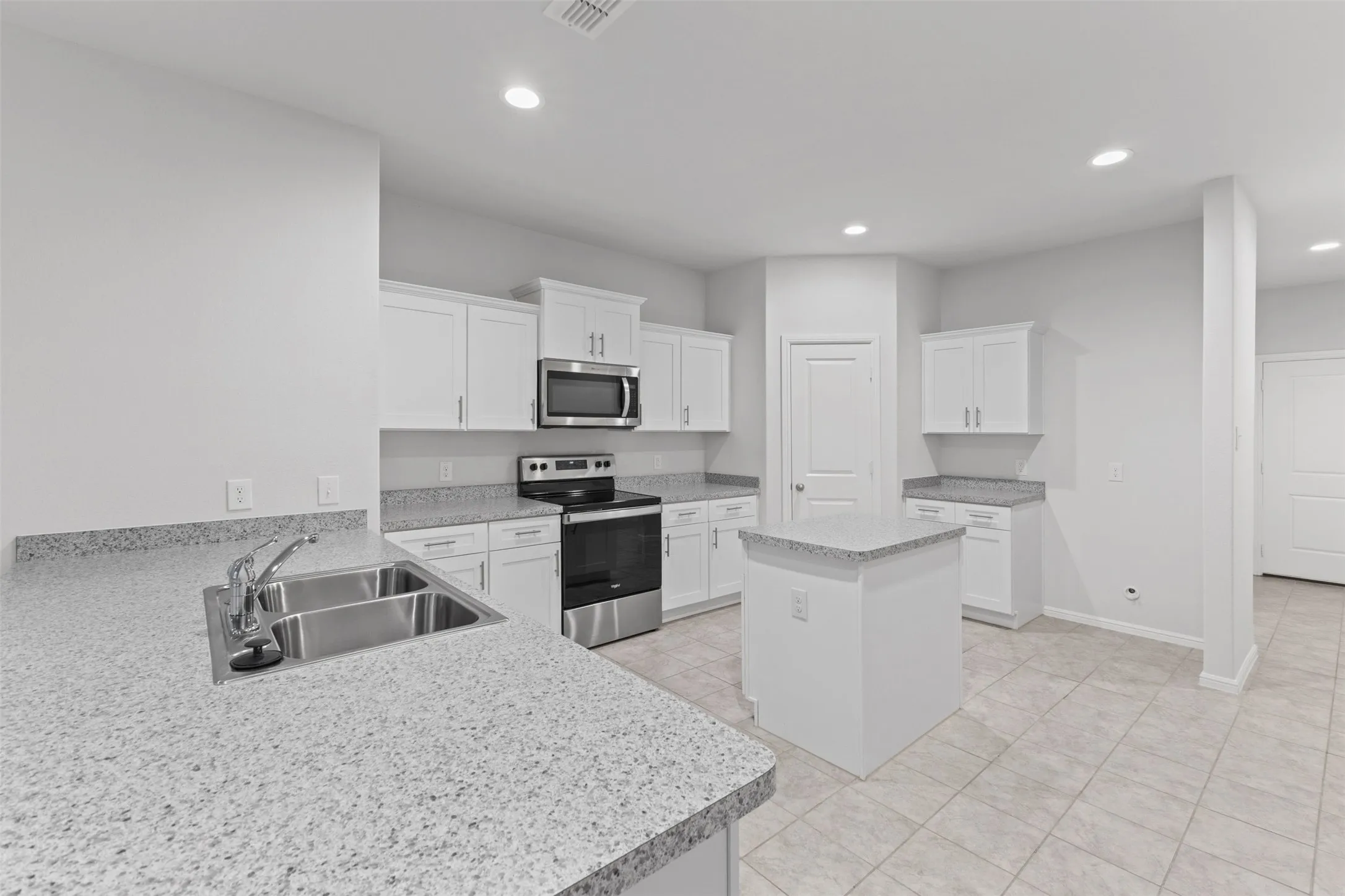 Well-appointed kitchen featuring white cabinetry, light-toned countertops, and a stainless steel appliance suite