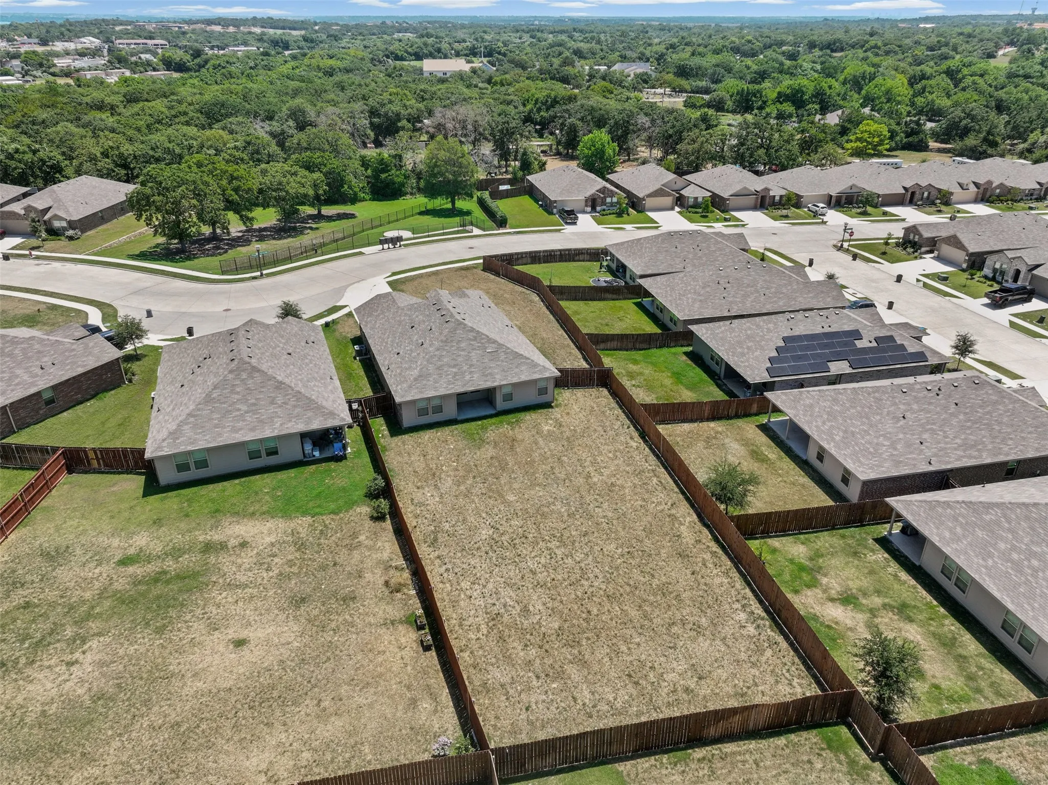 Expansive fenced backyard featuring mature trees and ample open space