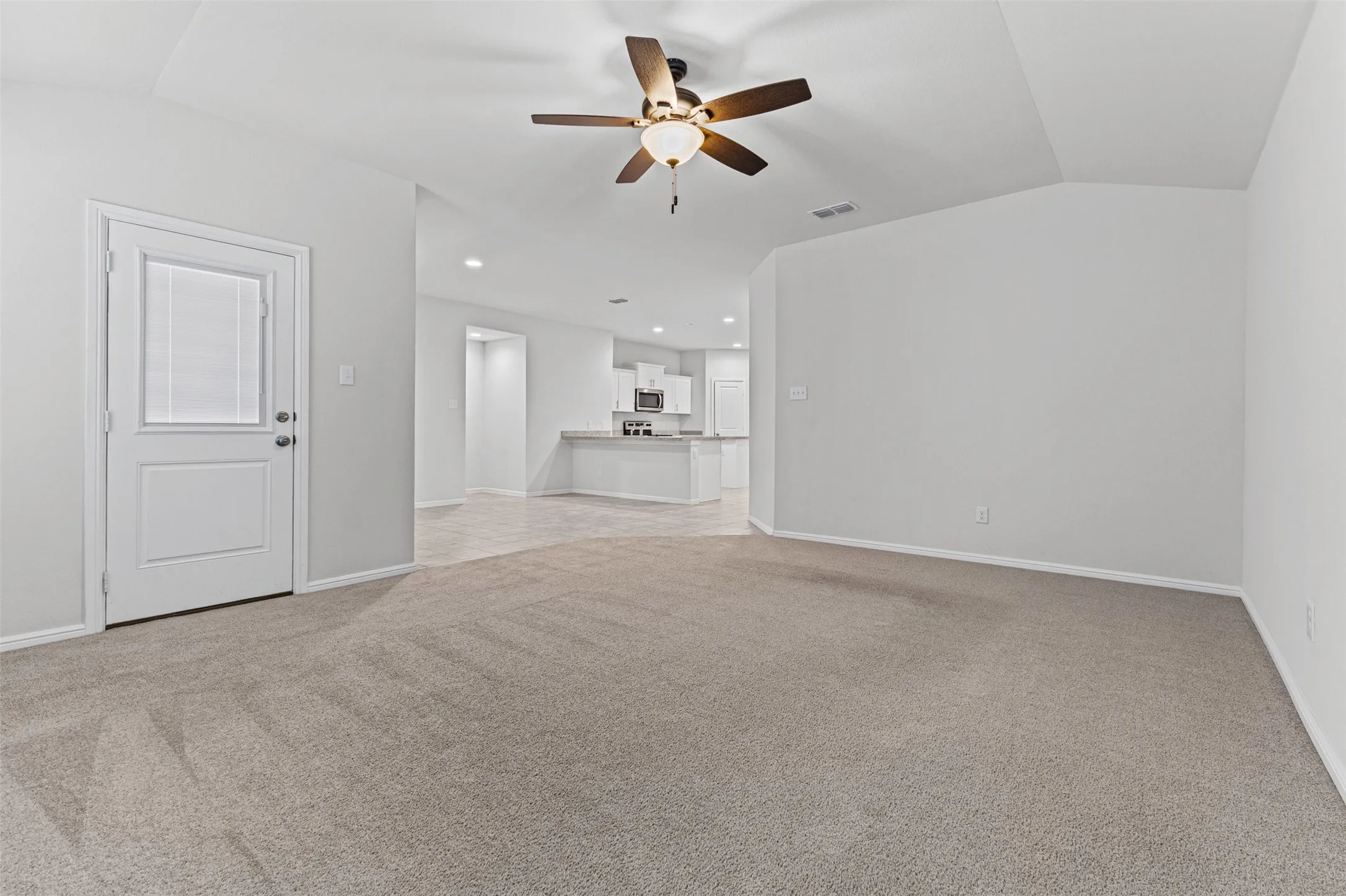 Carpeted living space featuring a ceiling fan with light fixture, recessed lighting, and a white paneled door with integrated blinds