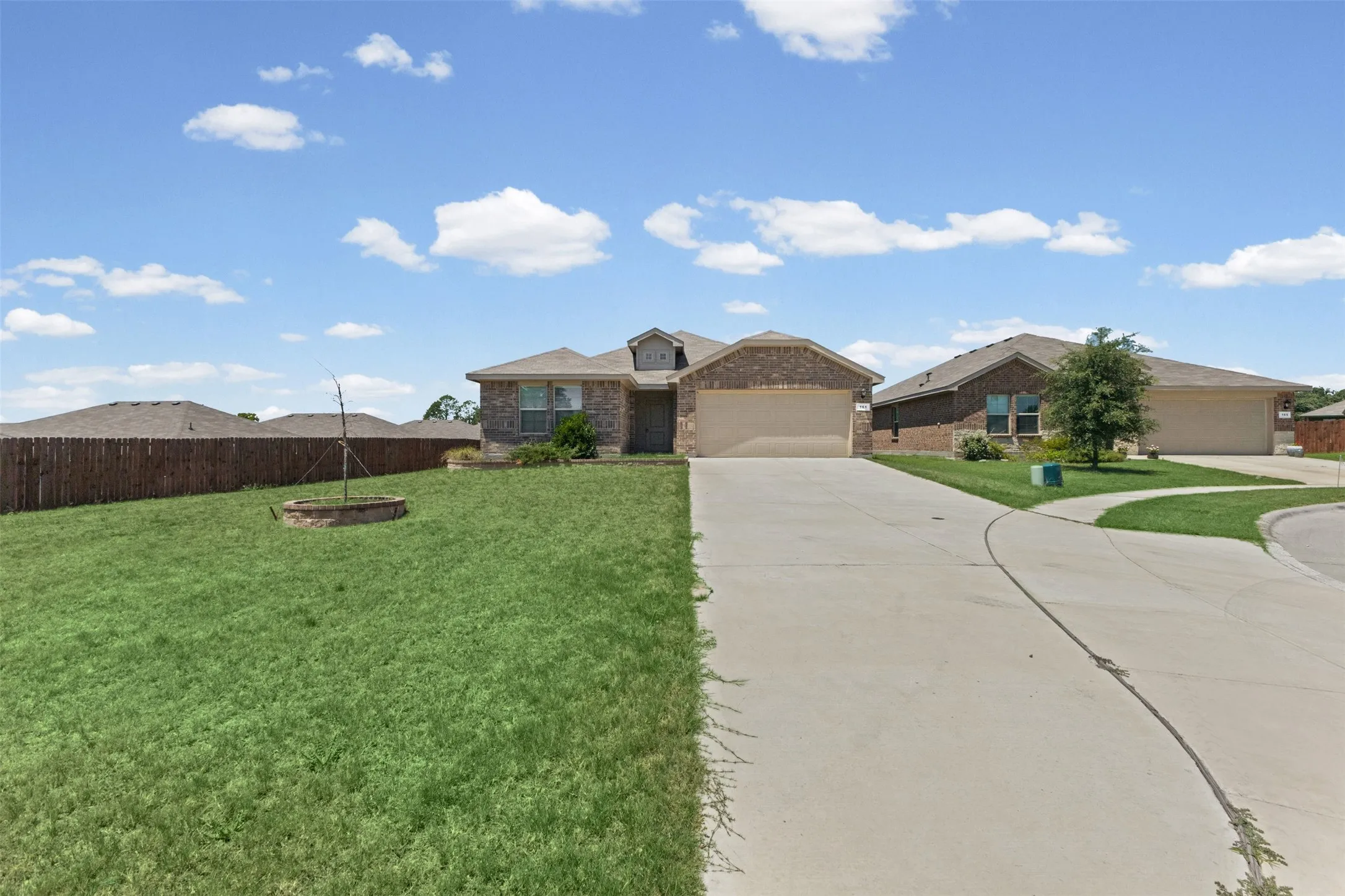 Brick exterior home featuring a two-car garage, concrete driveway, and front lawn