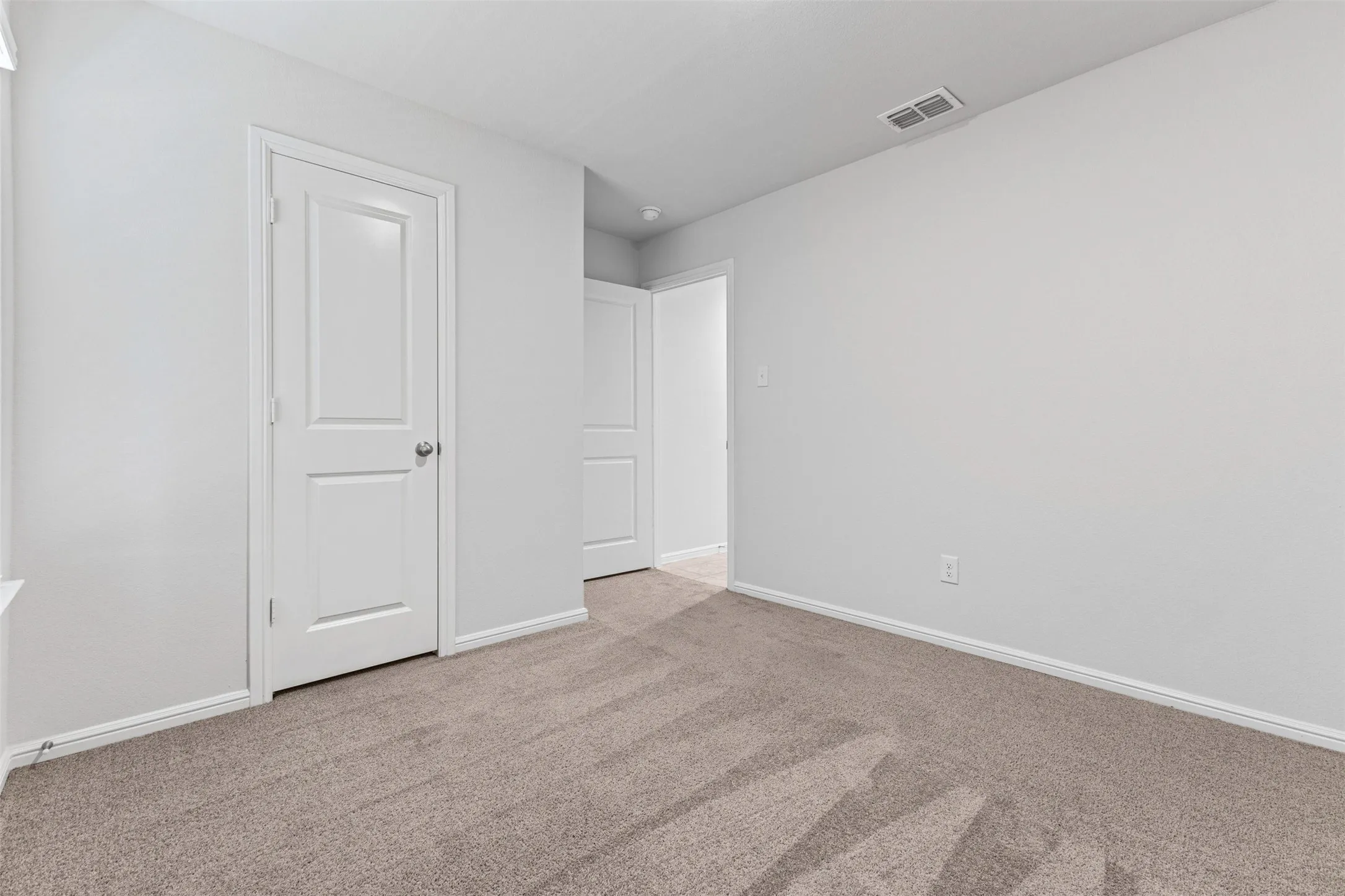 Carpeted interior room with white walls, white trim, and white paneled doors