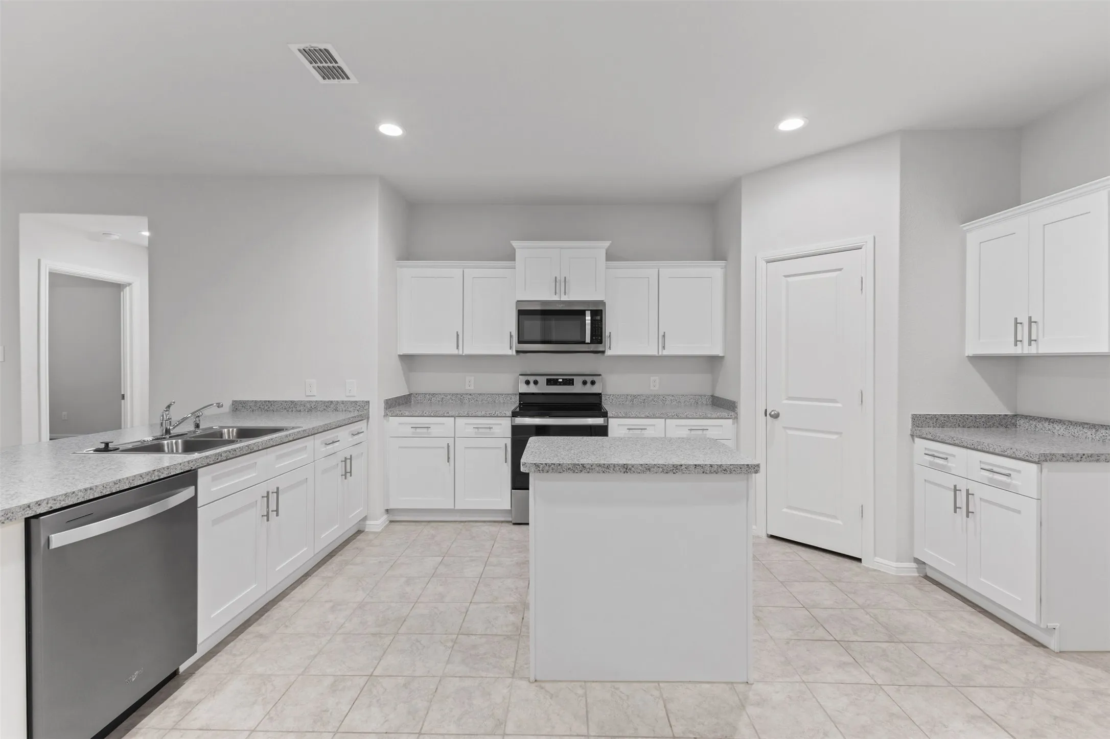 Modern kitchen featuring white cabinetry, light-toned countertops, a stainless steel dishwasher, a built-in microwave, and tile flooring