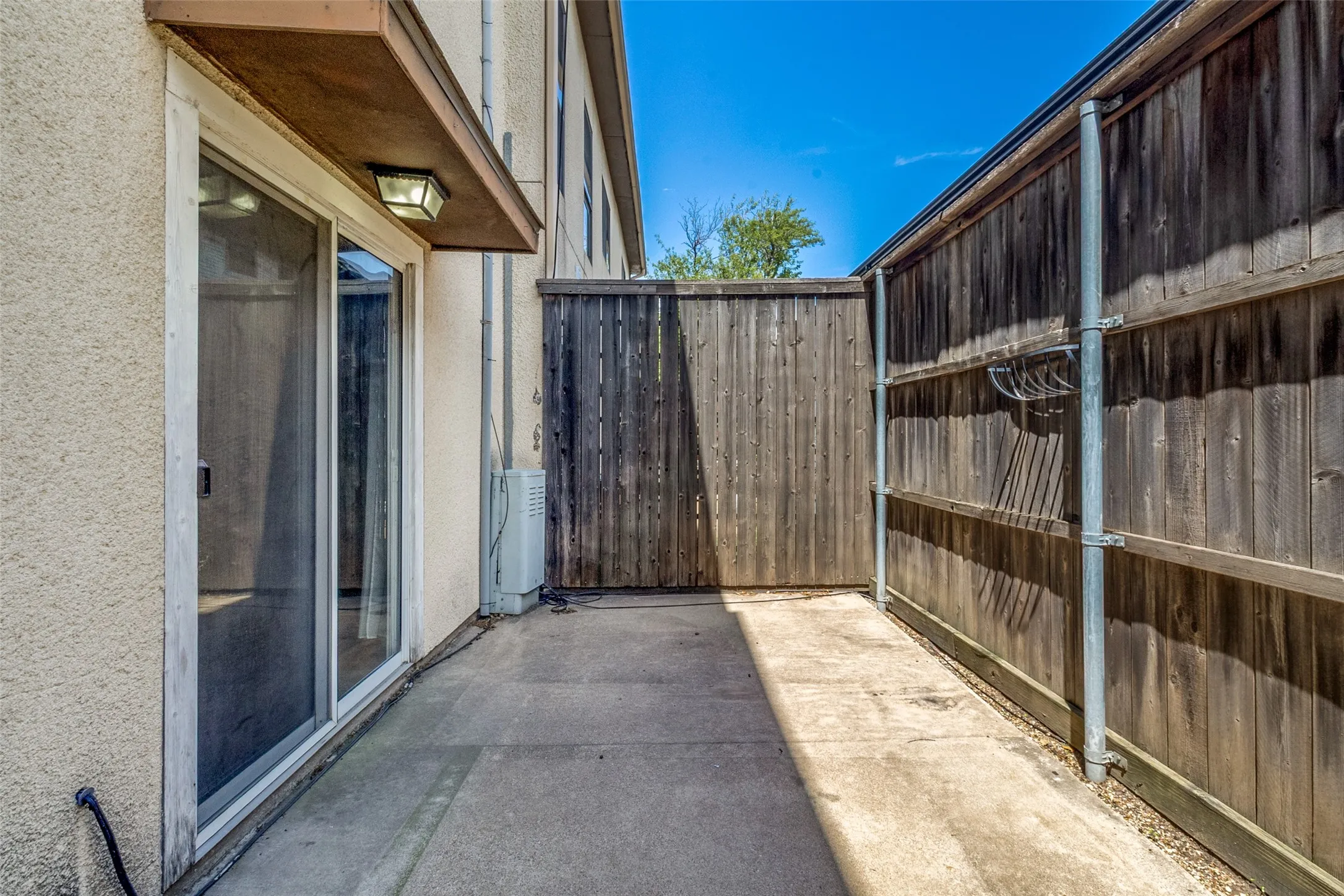 Private outdoor patio space featuring concrete flooring and tall wood fencing