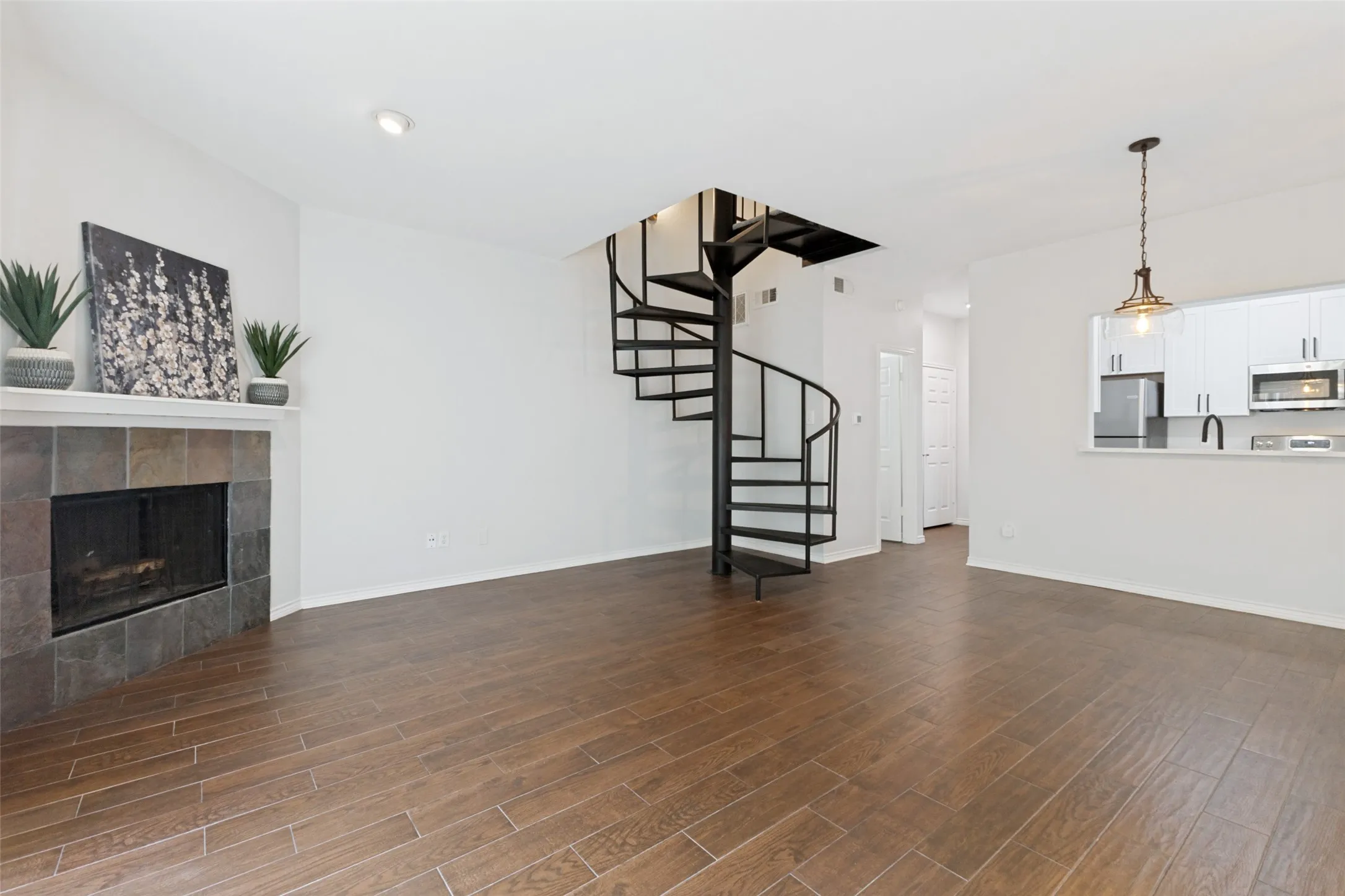 Spacious living area featuring a prominent black spiral staircase and wood-finish flooring