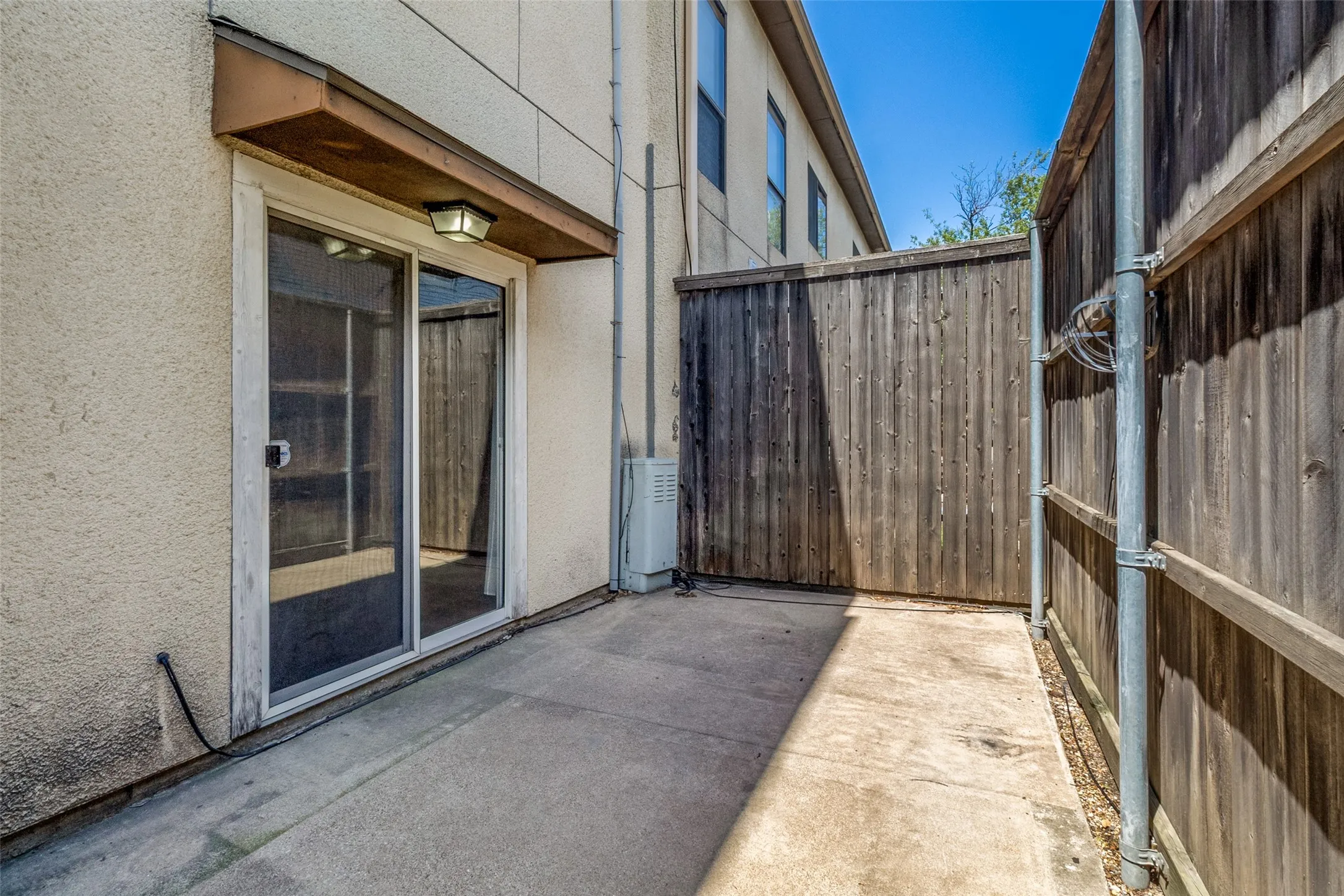 Private patio featuring a sliding glass door, overhead lighting, and concrete flooring