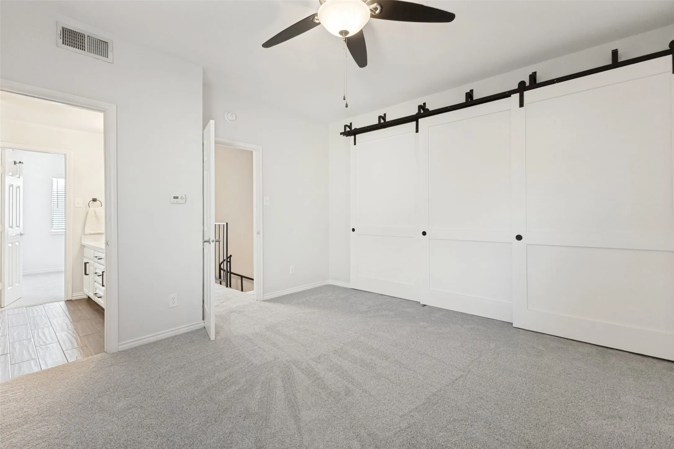 Neutral color palette featuring soft grey carpeting, white walls, and white trim with stately closet doors in white