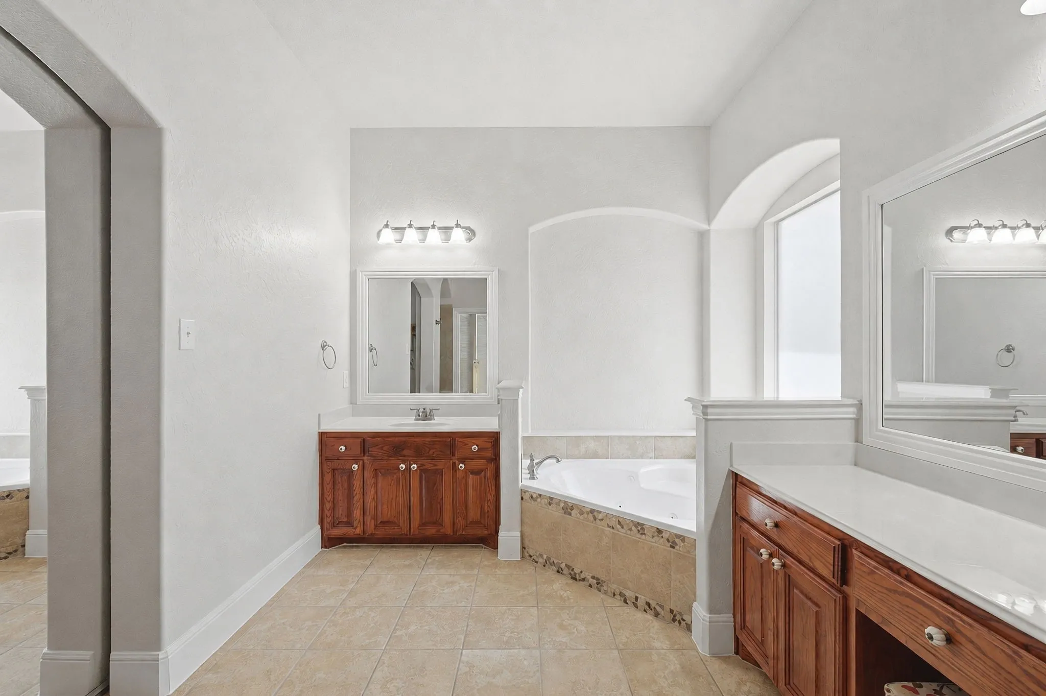 Primary Bathroom With Corner Jetted Tub And Dual Vanities.