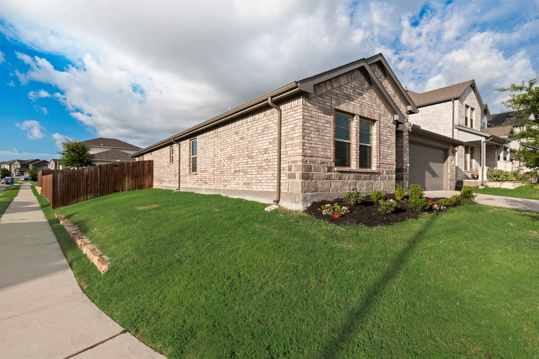 Brick exterior featuring light-toned brick and a darker stone accent base