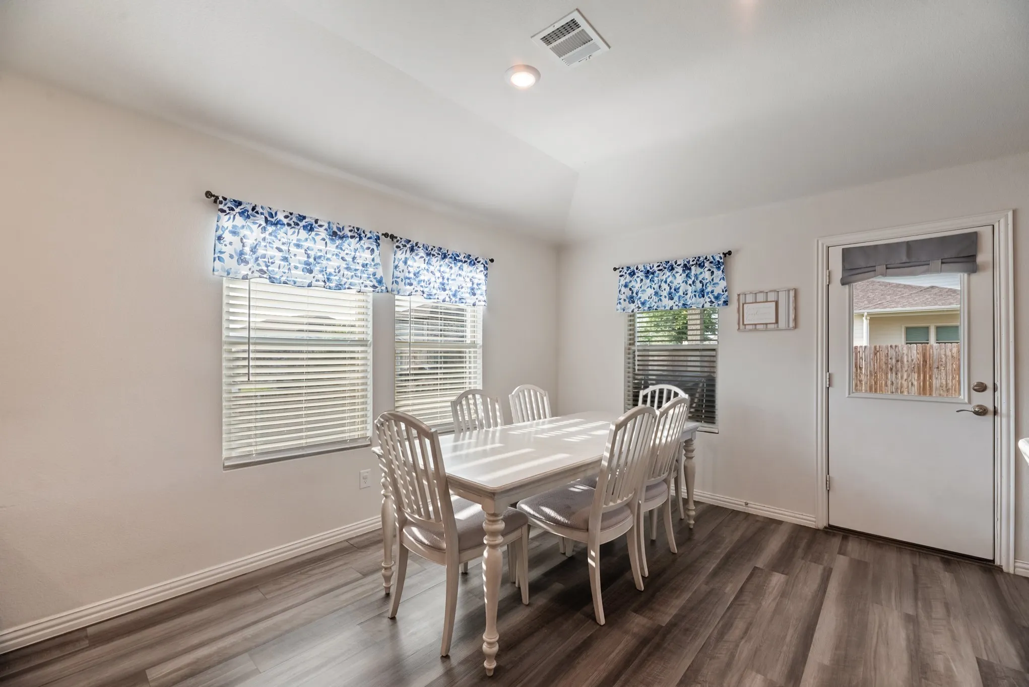 Dining area with wood-finish flooring, white baseboards, and a white door with a window