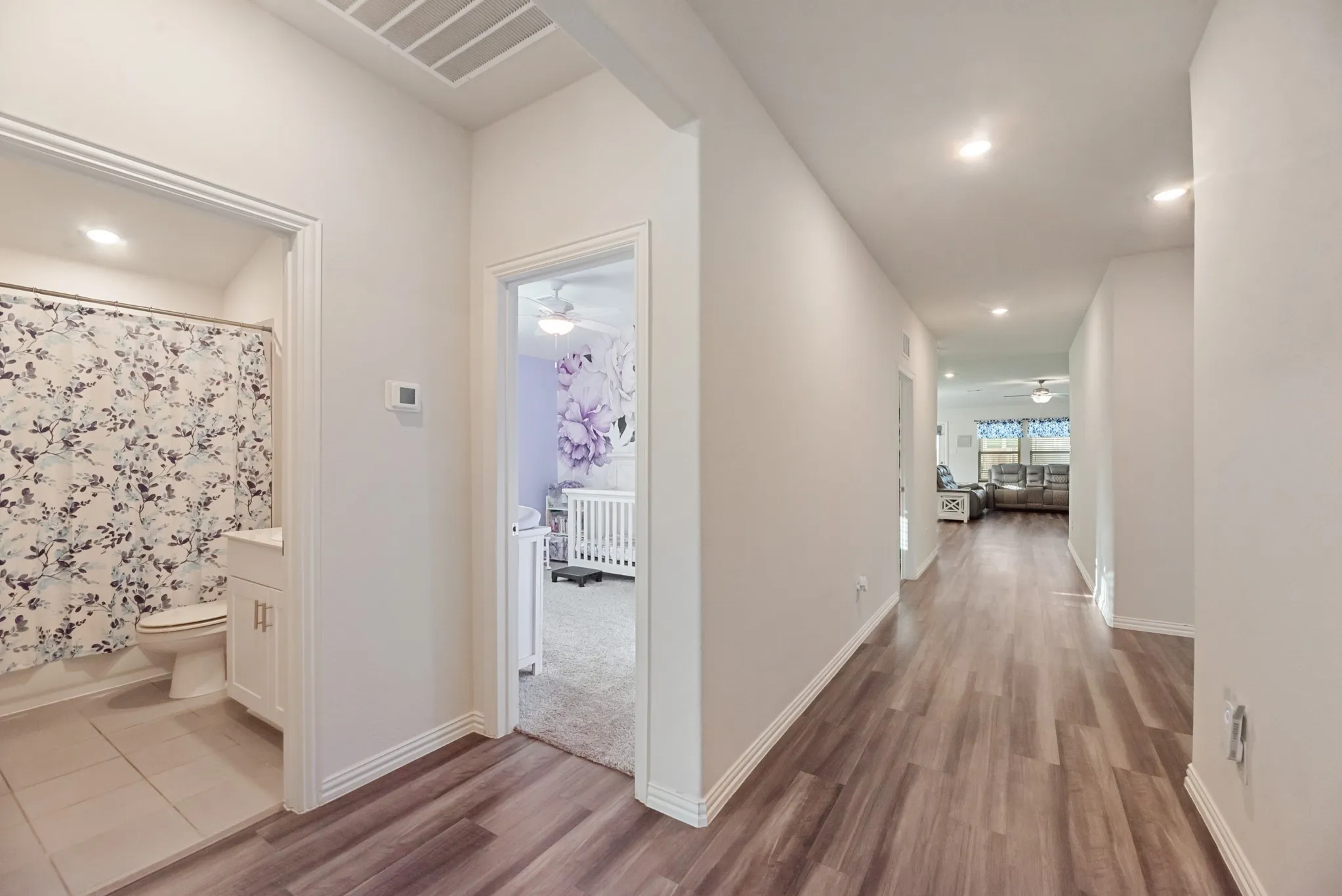 Hallway featuring wood-finish flooring, recessed lighting, and white baseboards