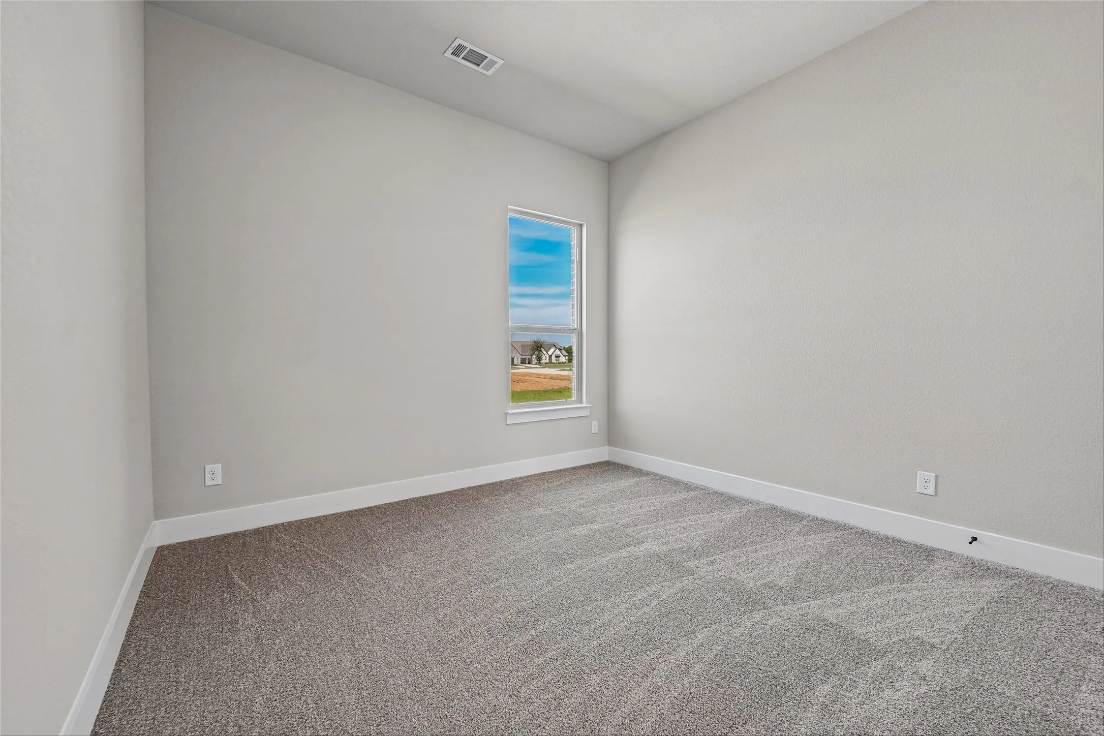 Grey carpet flooring, light neutral-toned walls, and a single window with white trim