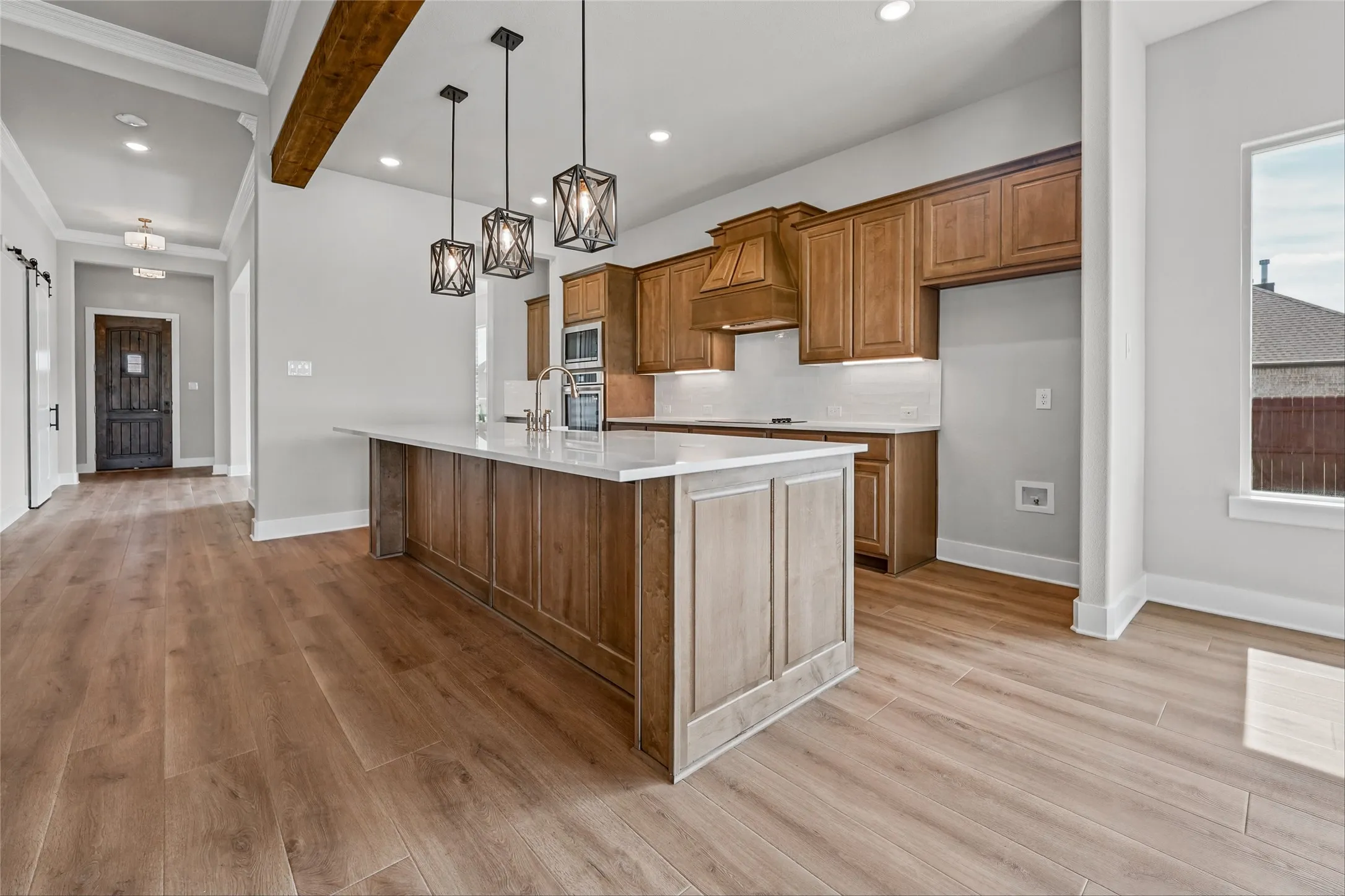 Kitchen featuring a wood-finish island with a light countertop, wood-finish cabinetry, stainless steel appliances, and pendant lighting