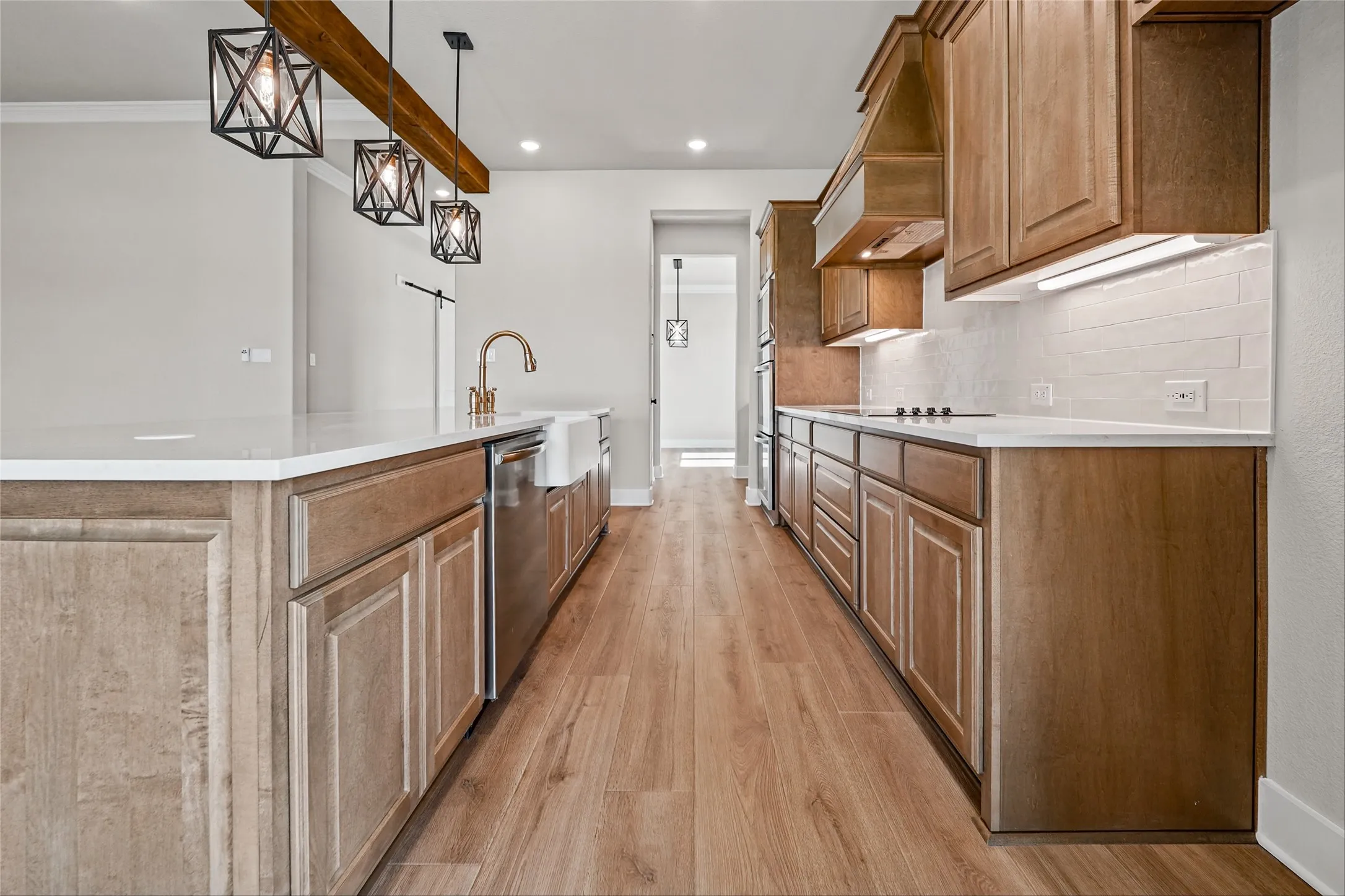 Kitchen featuring wood-finish flooring, a farmhouse sink, stainless steel appliances, white countertops, and warm wood cabinetry