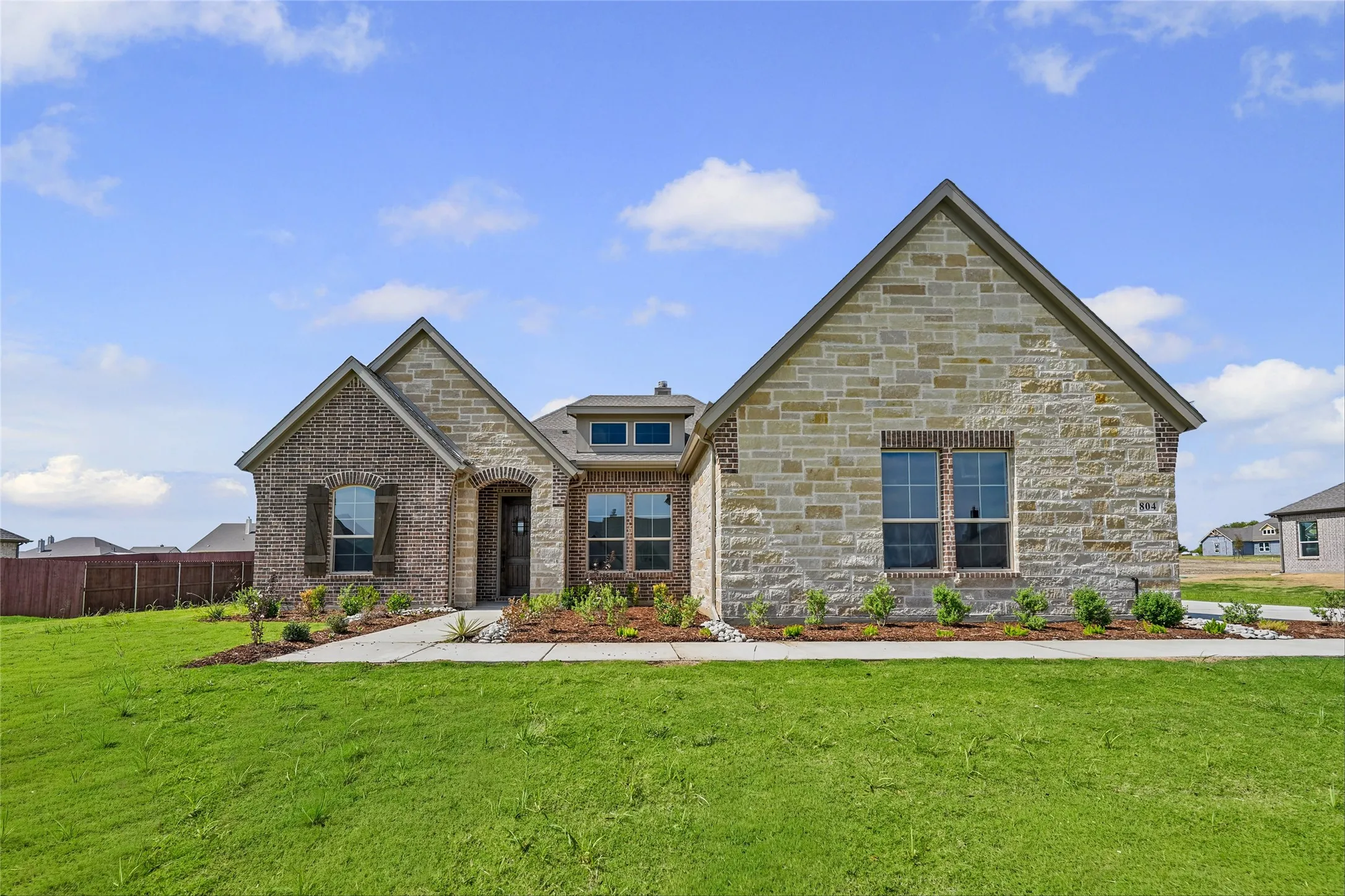 Stone and brick facade with gabled roof lines, arched entryway, and a concrete walkway