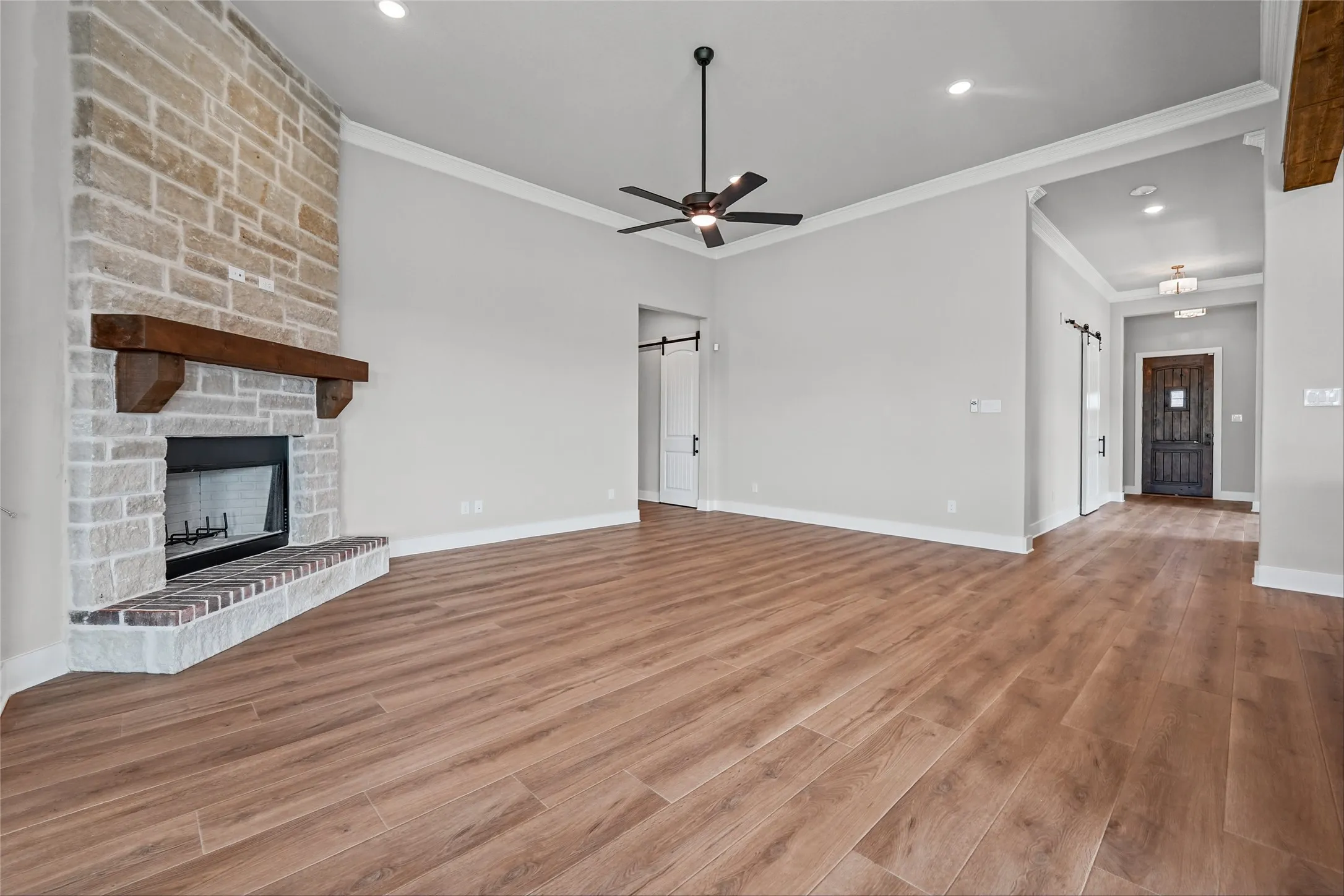 Stone fireplace with a wood mantel, wood-finish flooring, recessed lighting, and a ceiling fan