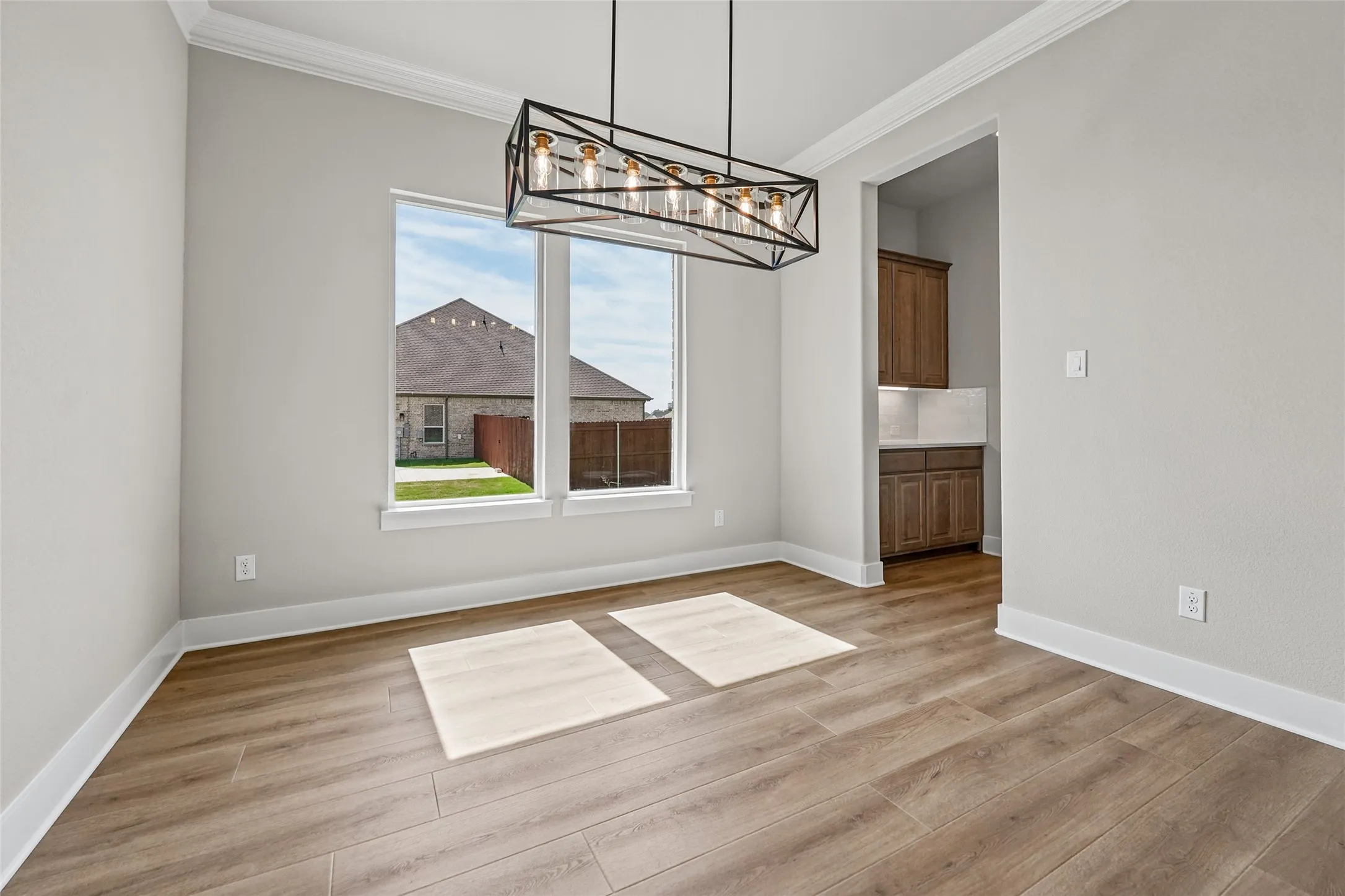 Wood-finish flooring, crown molding, and a modern rectangular chandelier