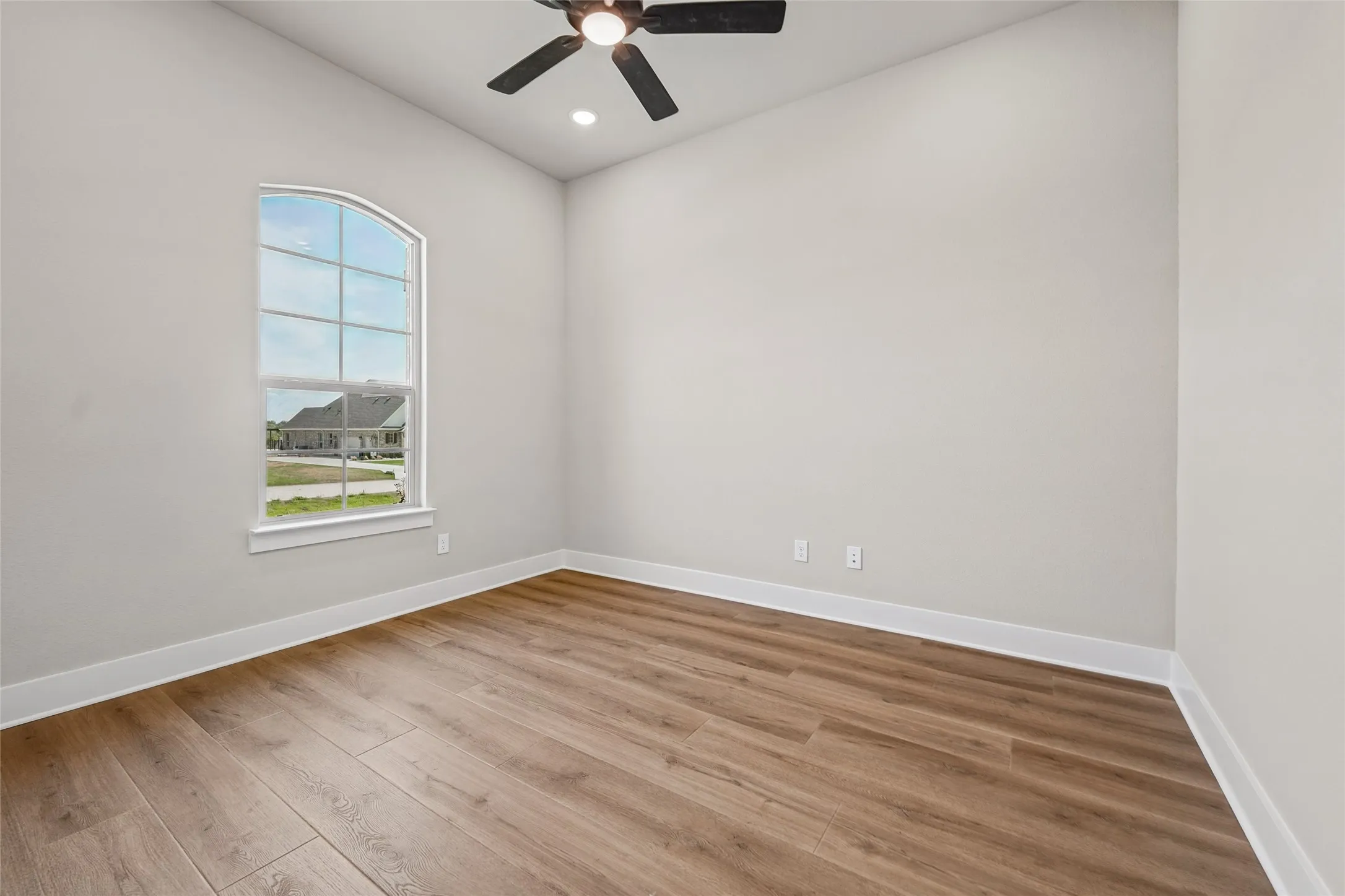 Arched window, wood-finish flooring, recessed lighting, and ceiling fan