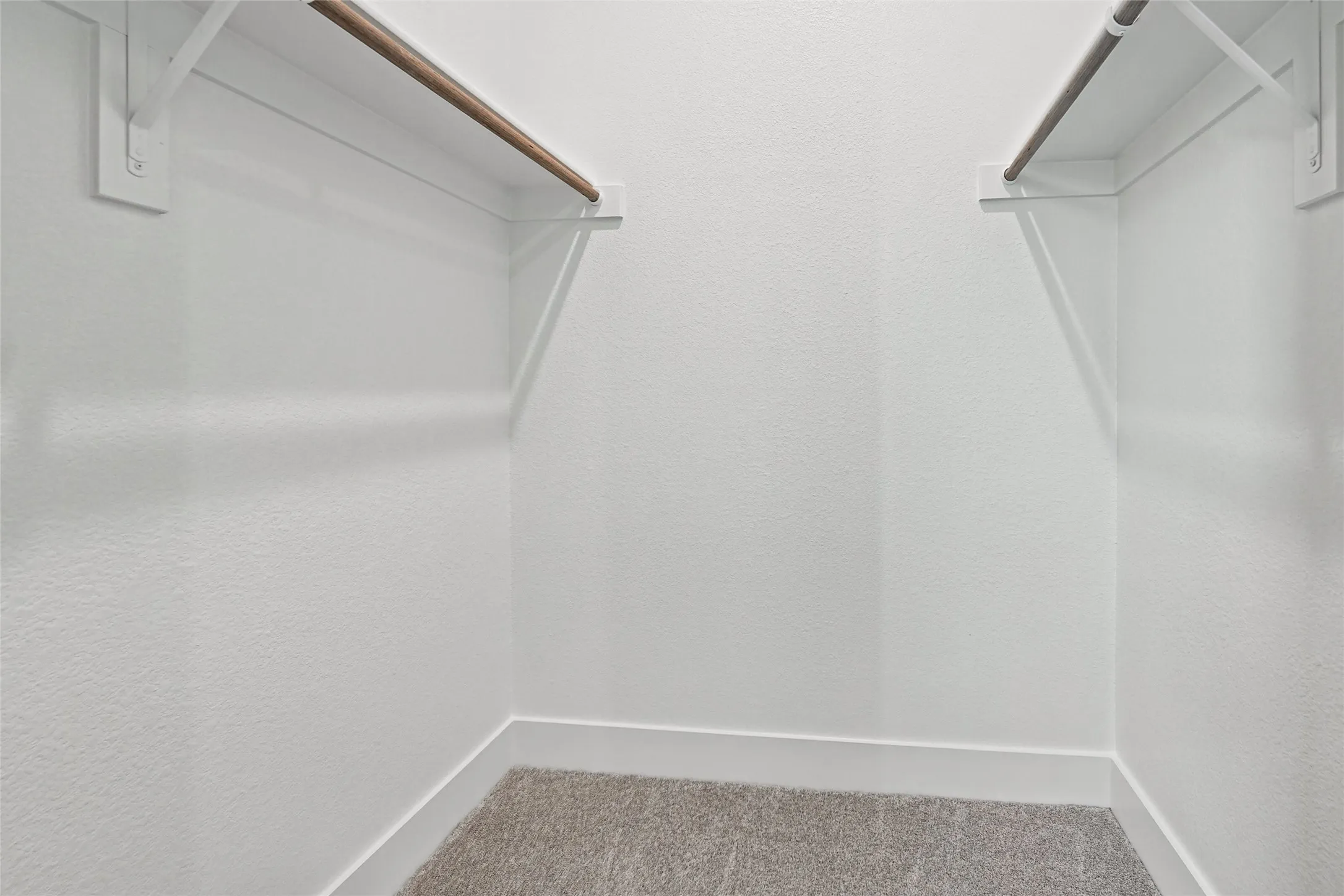Walk-in closet with carpet flooring and dual wood-finish hanging rods