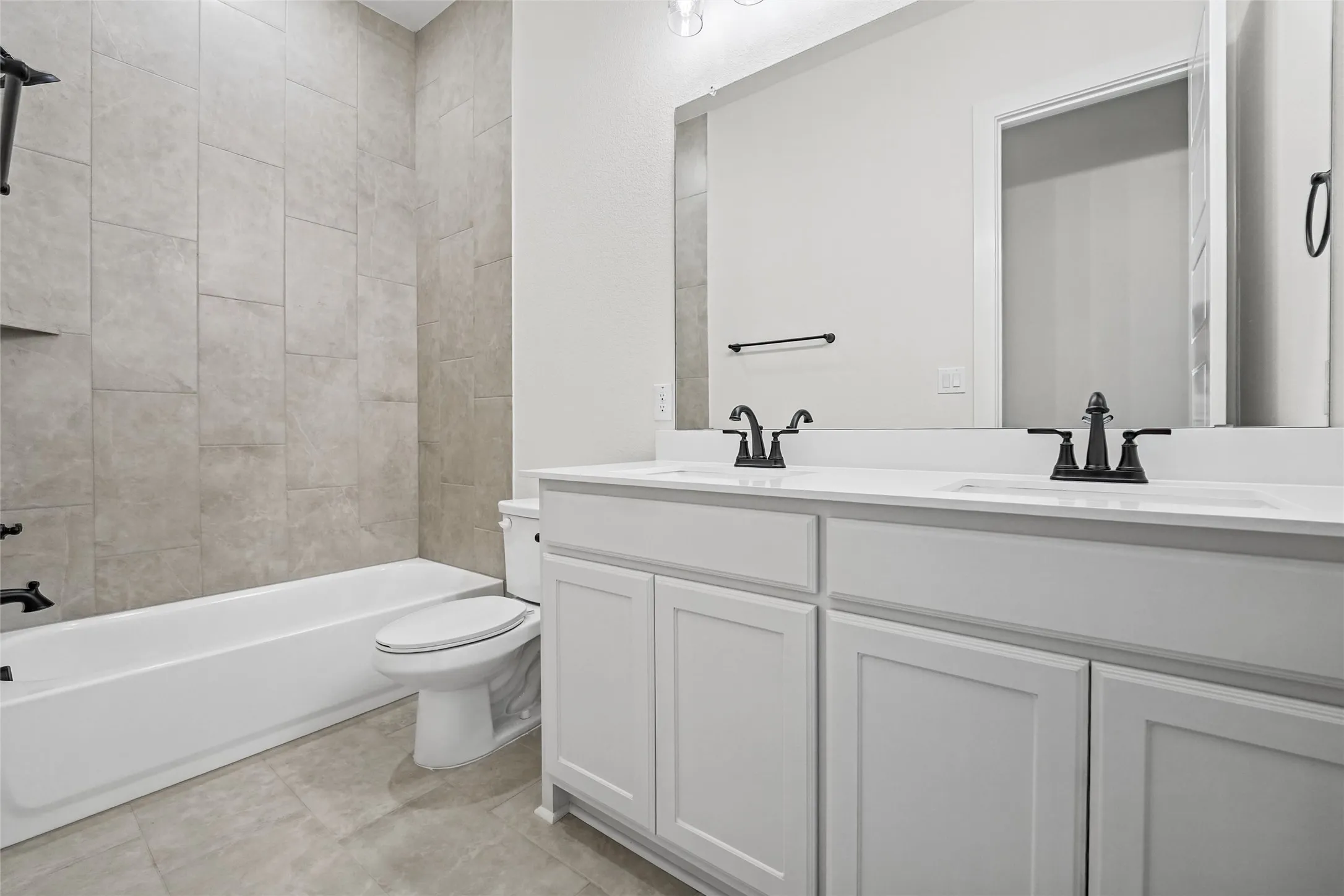 White dual-sink vanity with matte black fixtures, white countertop, and integrated mirror