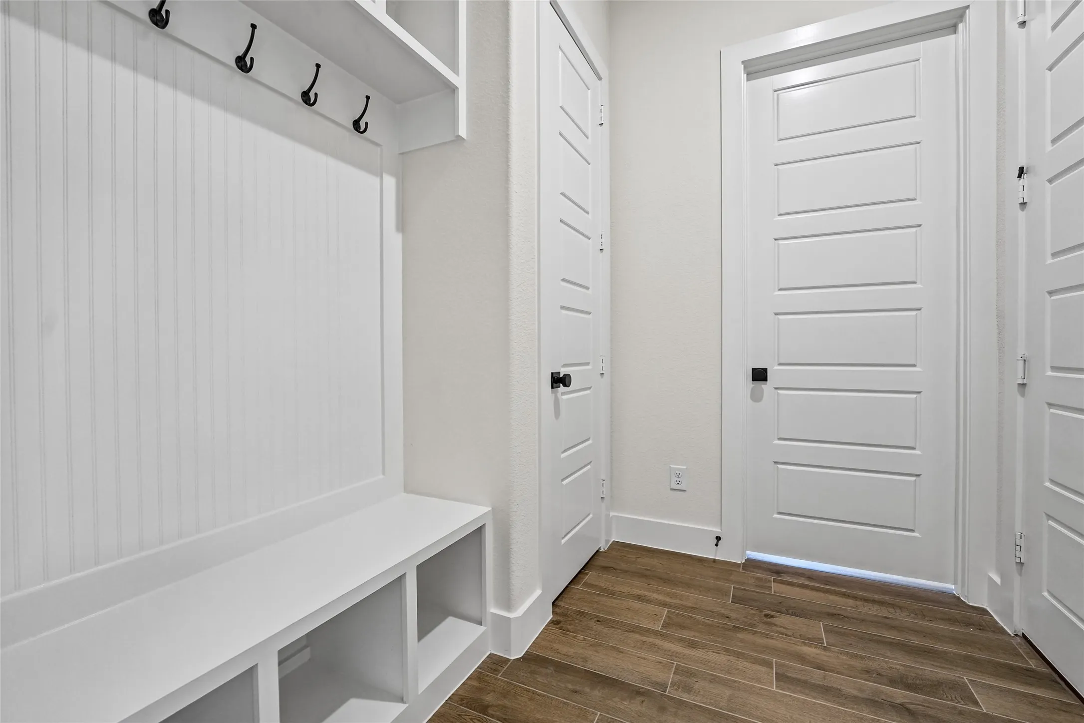 Built-in bench with cubby storage, beadboard paneling, and wall hooks