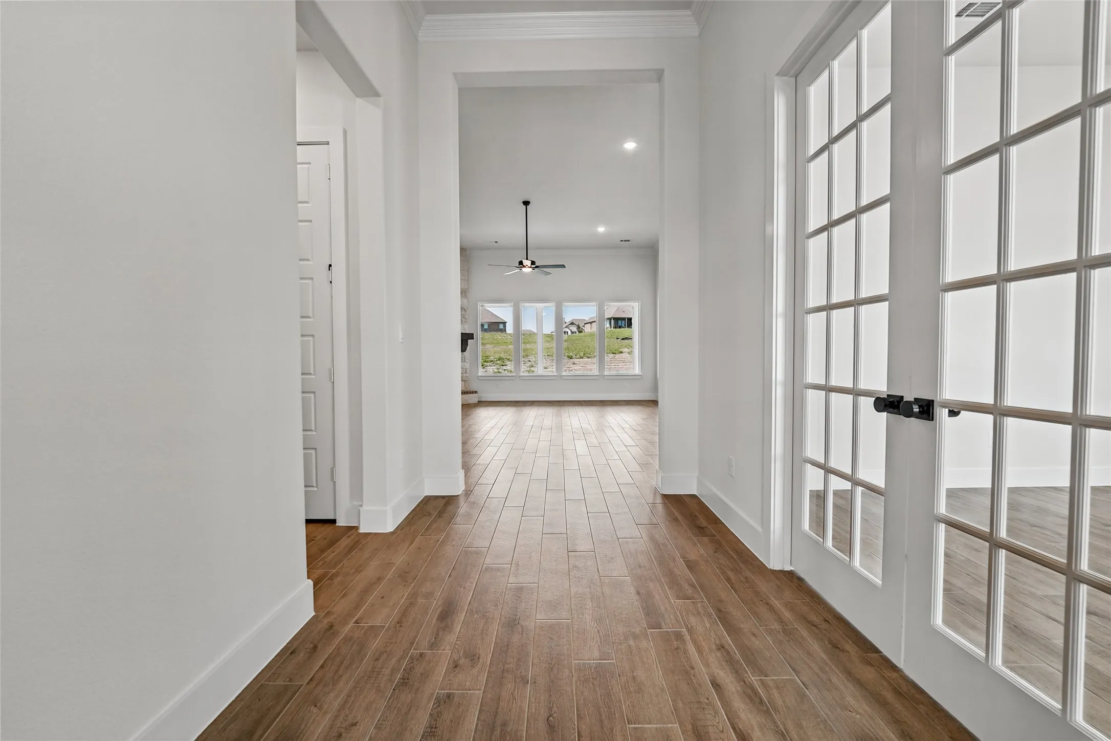 Wood-finish flooring throughout, white walls, and crown molding