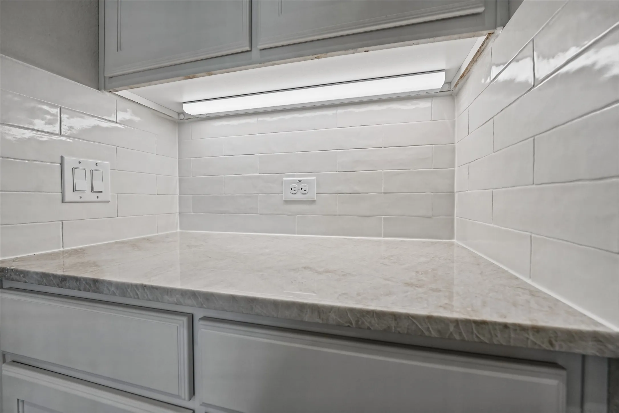 Undercabinet lighting illuminates the light-toned countertop, complemented by a white subway tile backsplash