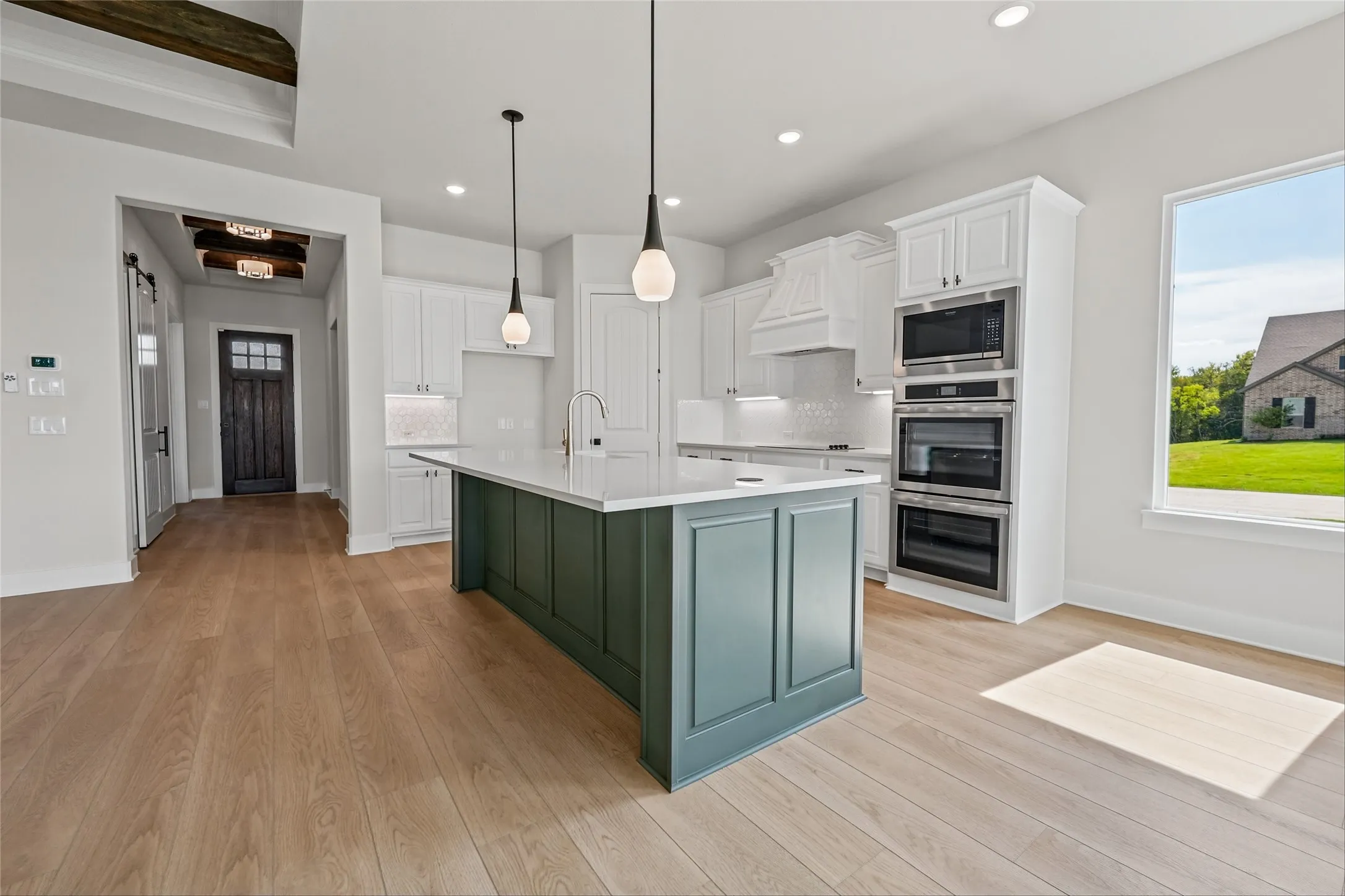 Spacious kitchen featuring an expansive center island, integrated stainless steel appliances, and wood-finish flooring