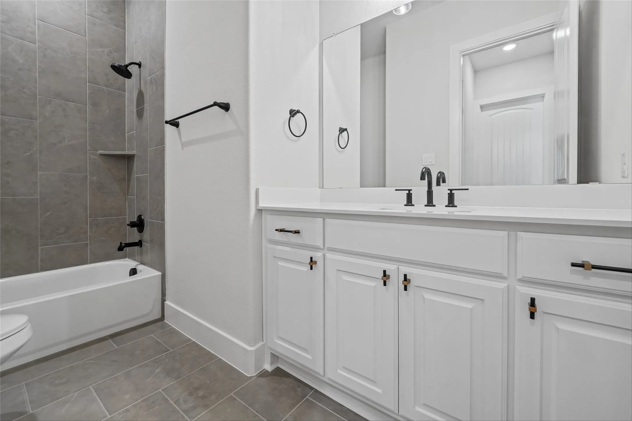 White vanity with an integrated sink, matte black fixtures, and a large mirror