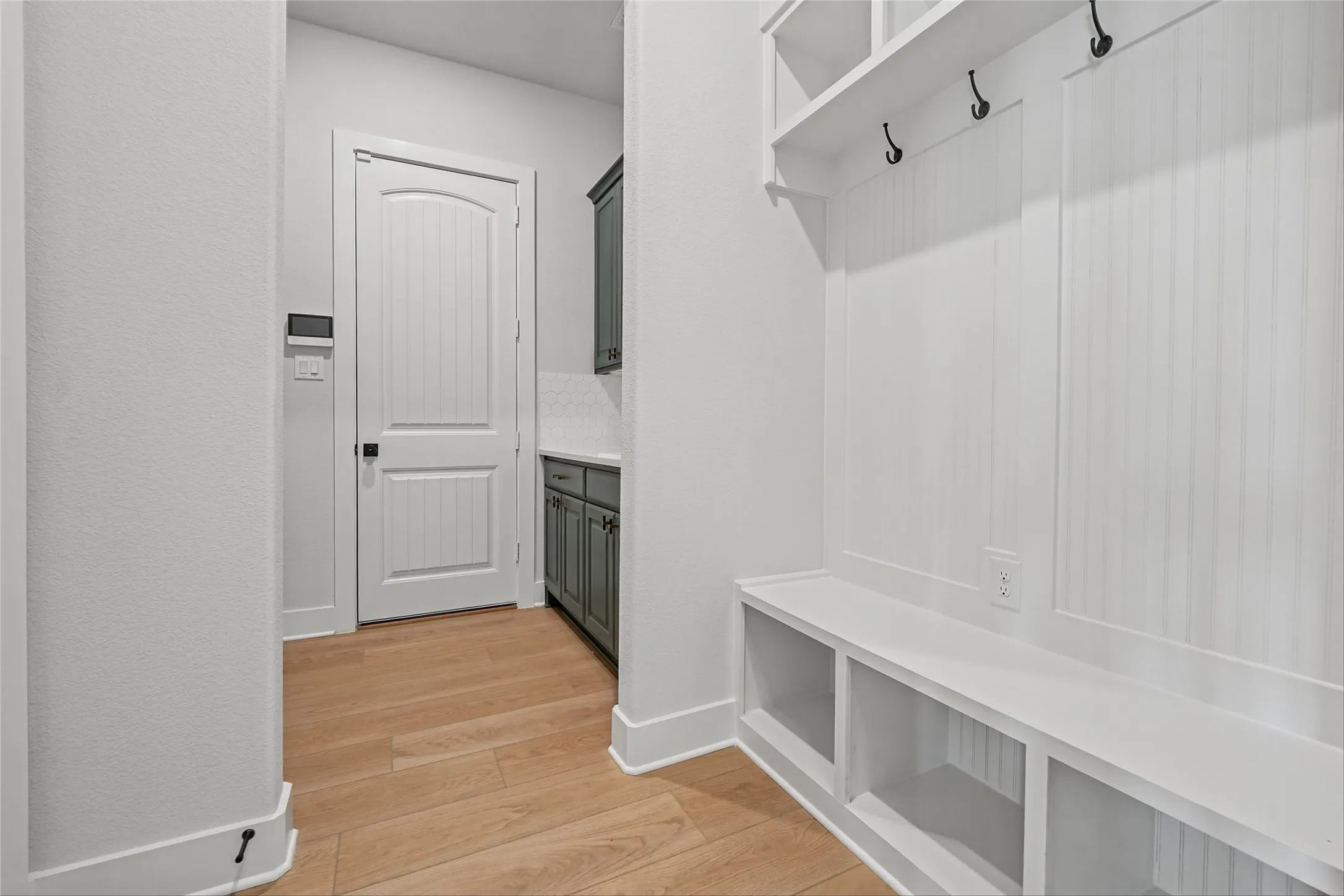 Built-in storage bench with cubbies, upper shelving, and coat hooks
