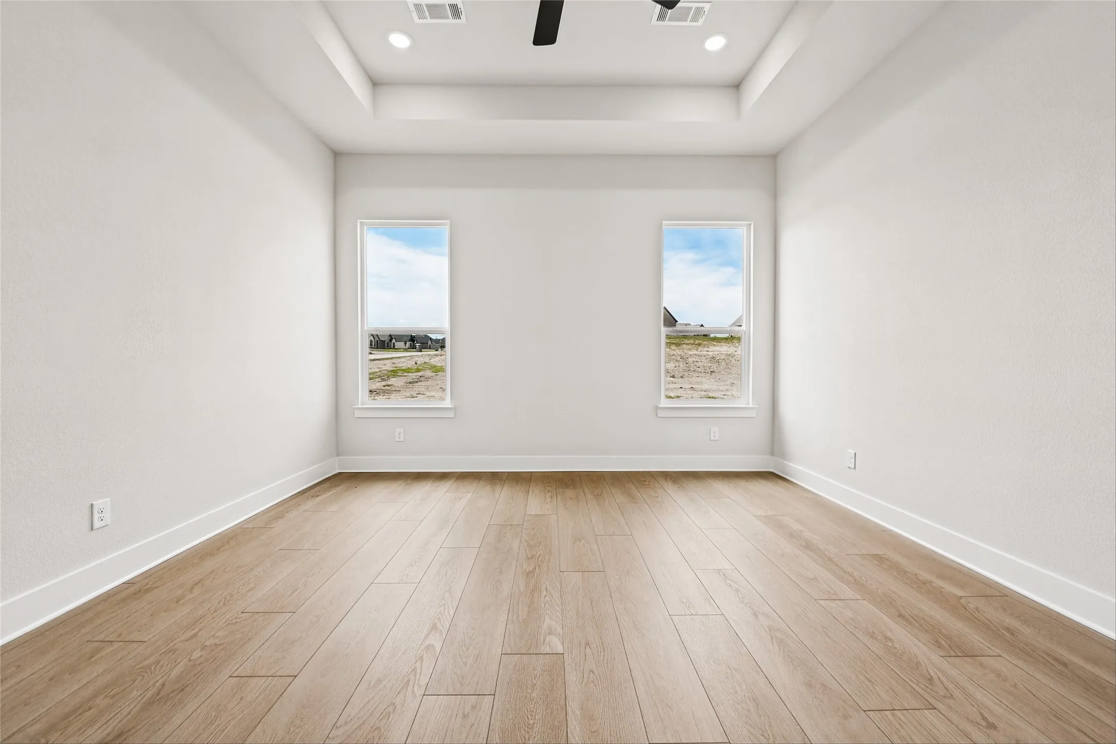 Recessed lighting, ceiling fan, tray ceiling, wood-finish flooring, and dual vertical windows