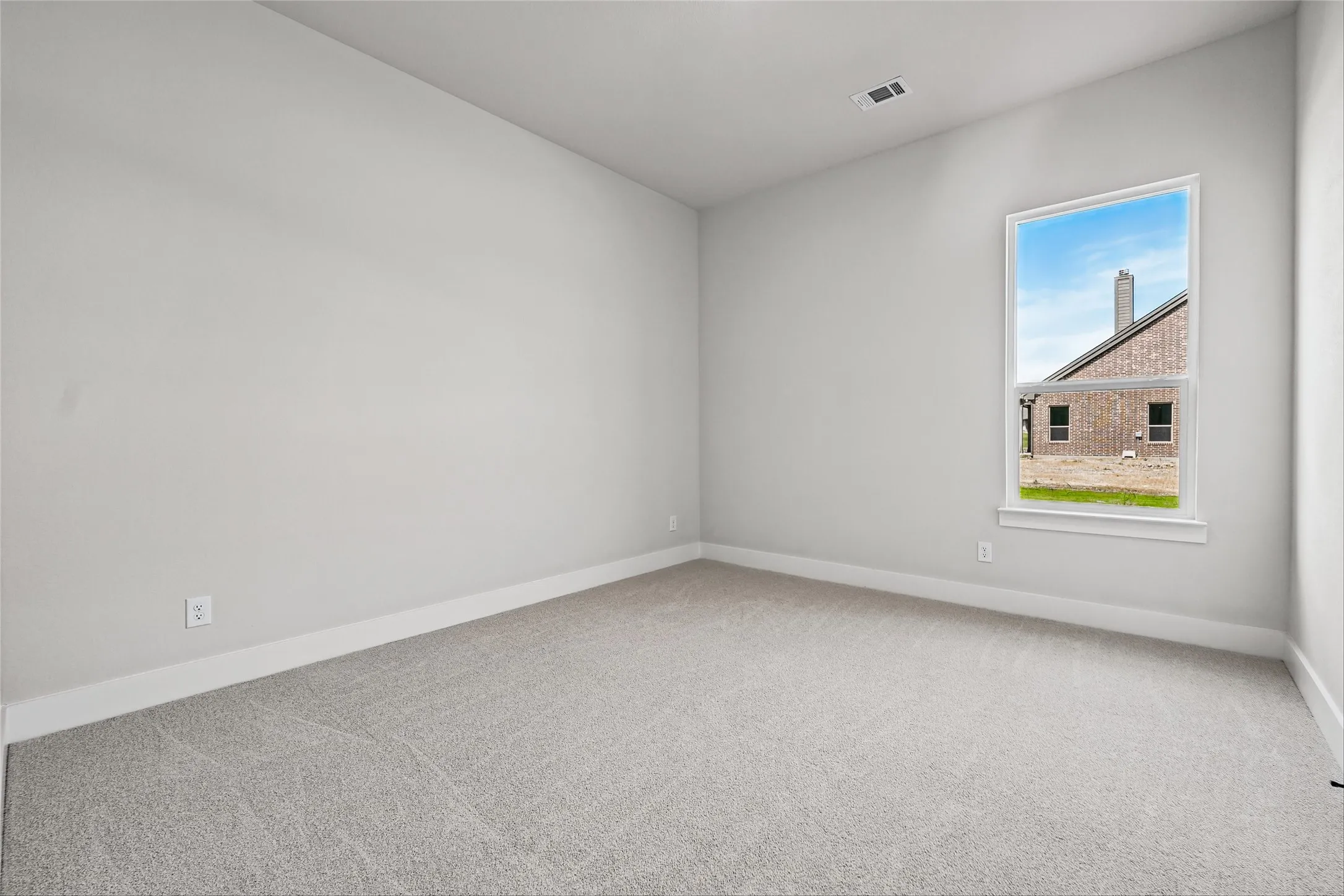 Carpeted room featuring a single-hung window with a white frame and light gray walls