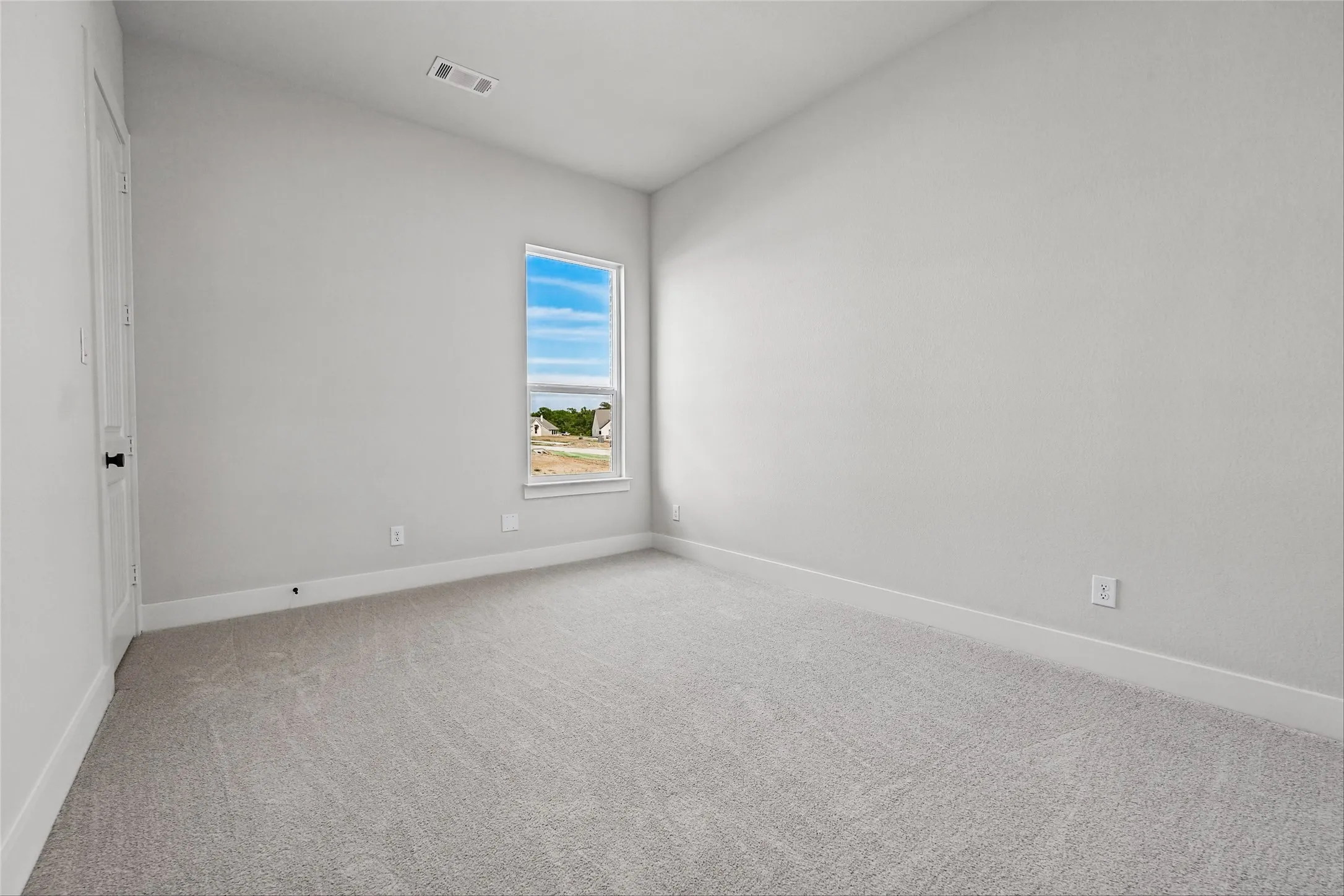 White interior walls, light gray carpet, and a single window with white trim