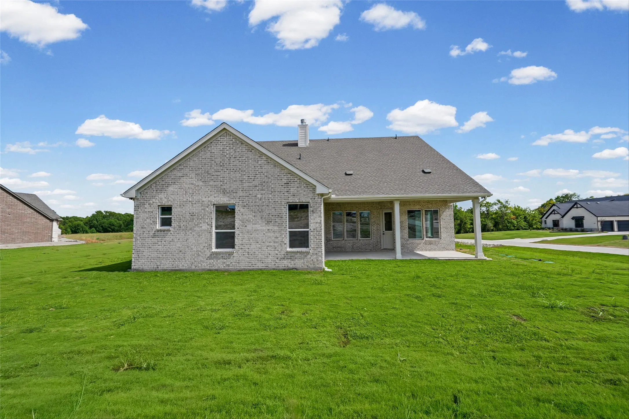 Brick exterior with a gabled roof and covered patio featuring support columns