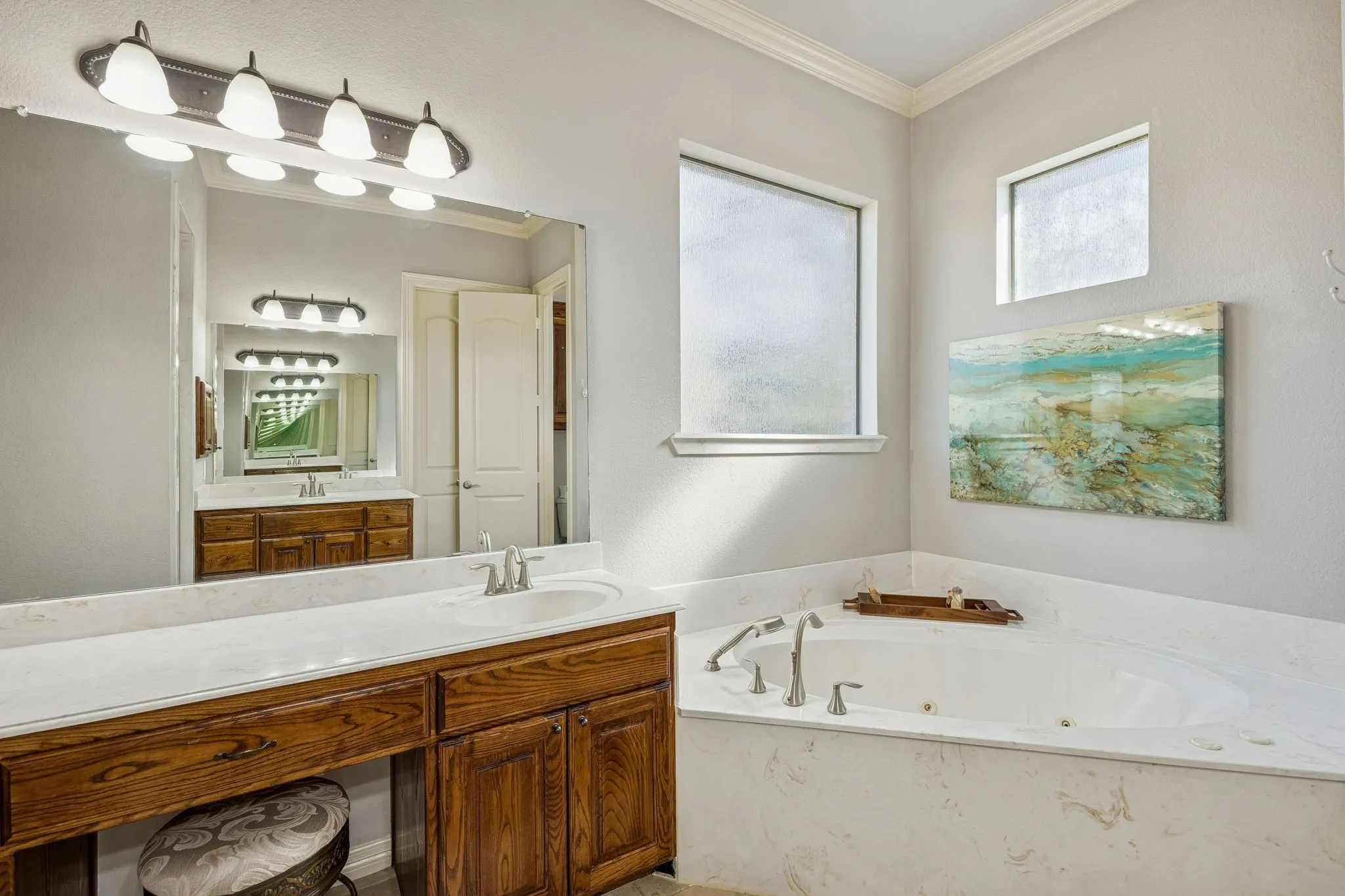 Primary suite features split vanities, one with a knee space, walk in shower, jetted tub, and private commode room.