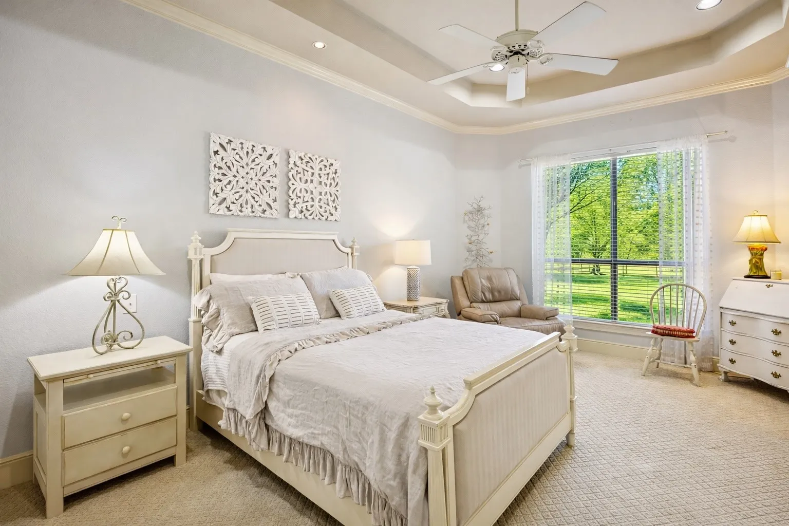 This second primary bedroom, or Mother-in-law suite, is on the first floor and has a large ensuite. Notice the tray ceiling and large window that offers lots of natural light and views of the lovely property.