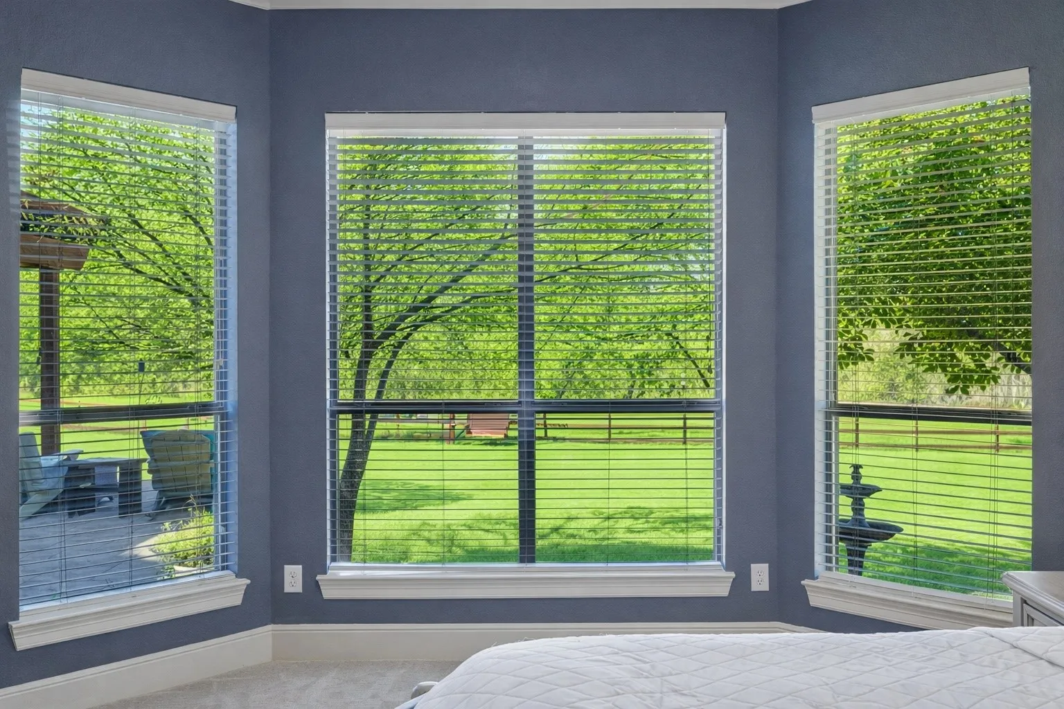 View of the mature landscaping in the backyard from the bay windows in the primary bedroom showcasing the peaceful views.