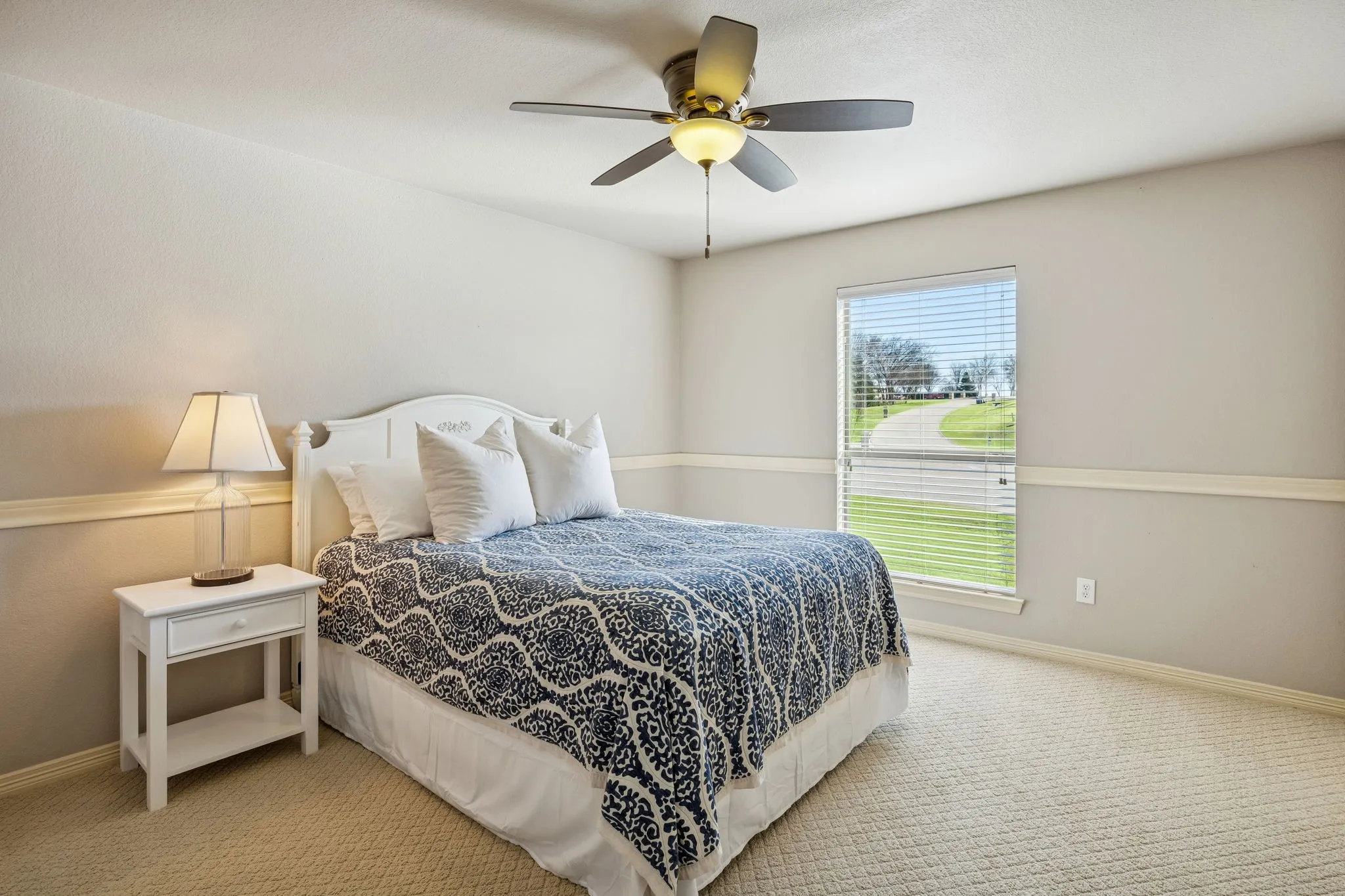 This secondary bedroom on the second floor features soft natural light and neutral-toned walls with wainscoting. There is a full bathroom next to this bedroom. Great for guest use.