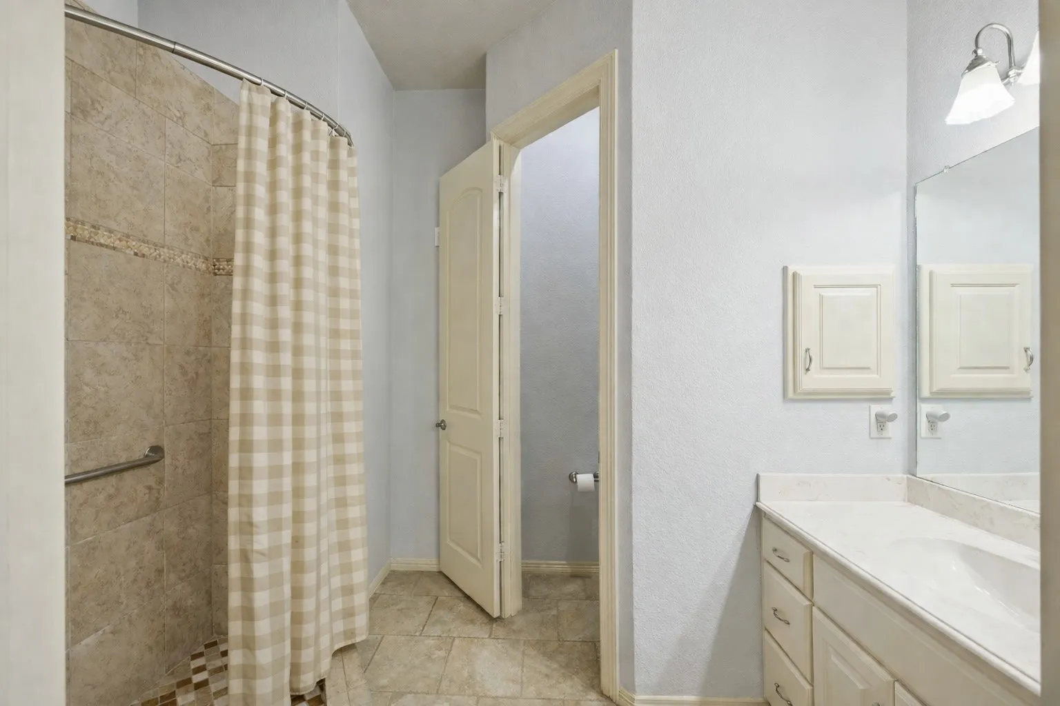 Secondary primary bathroom with tiled walk-in shower, large vanity, water closet, and a bright, well-maintained feel.