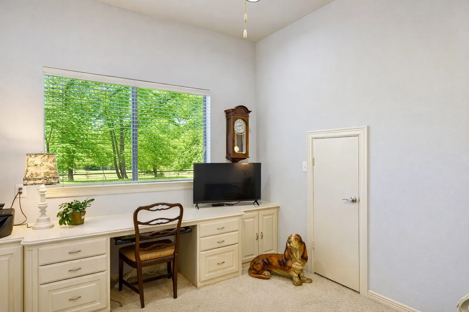Dedicated home office with built-in desk and cabinetry, offering ample storage and a bright workspace with scenic outdoor views.