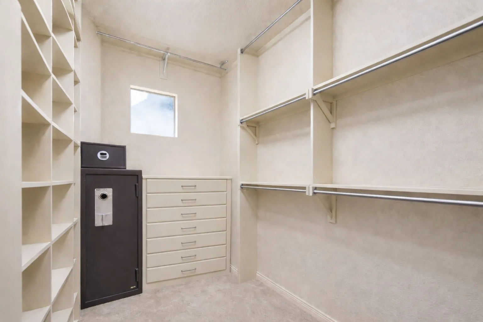 The primary bedroom closet features a built-in safe, shelving, and hanging rods, offering plenty of storage space.