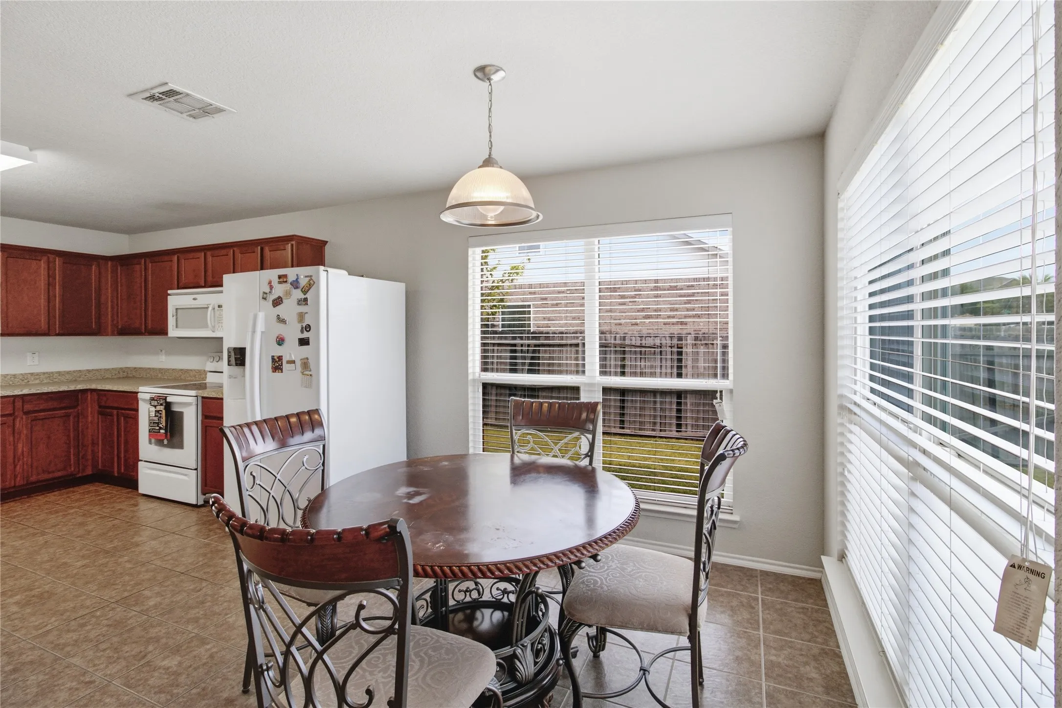 Kitchen area featuring warm wood-finish cabinetry, white appliances, and a light-toned countertop