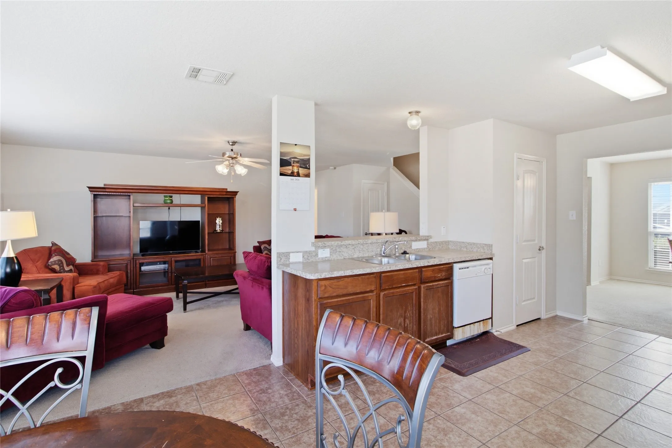 Kitchen featuring a double basin sink, light-toned countertop, wood-finish cabinetry, and tiled flooring