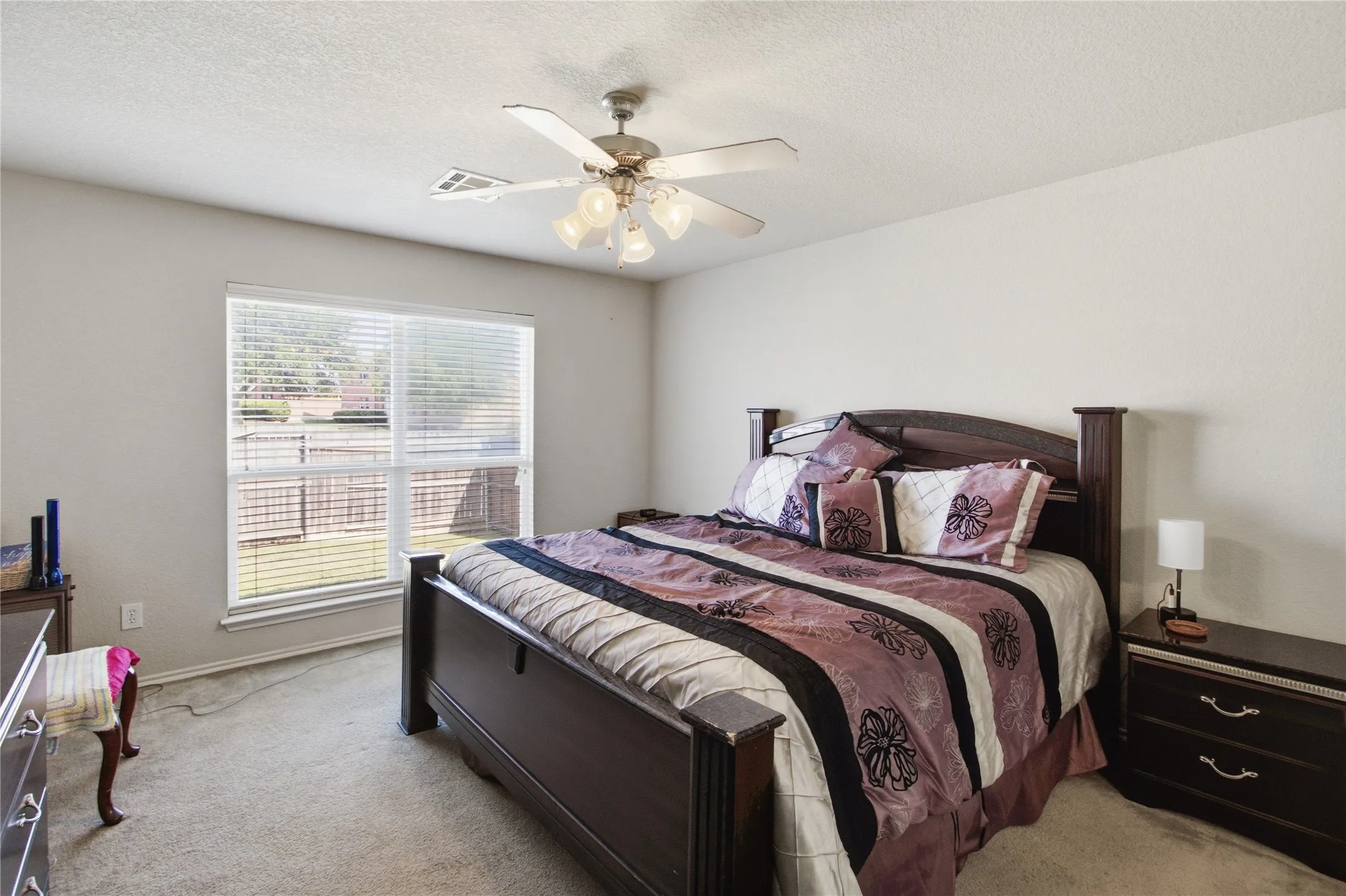 Carpeted room featuring a large window with blinds, a ceiling fan with integrated lighting, and neutral wall paint